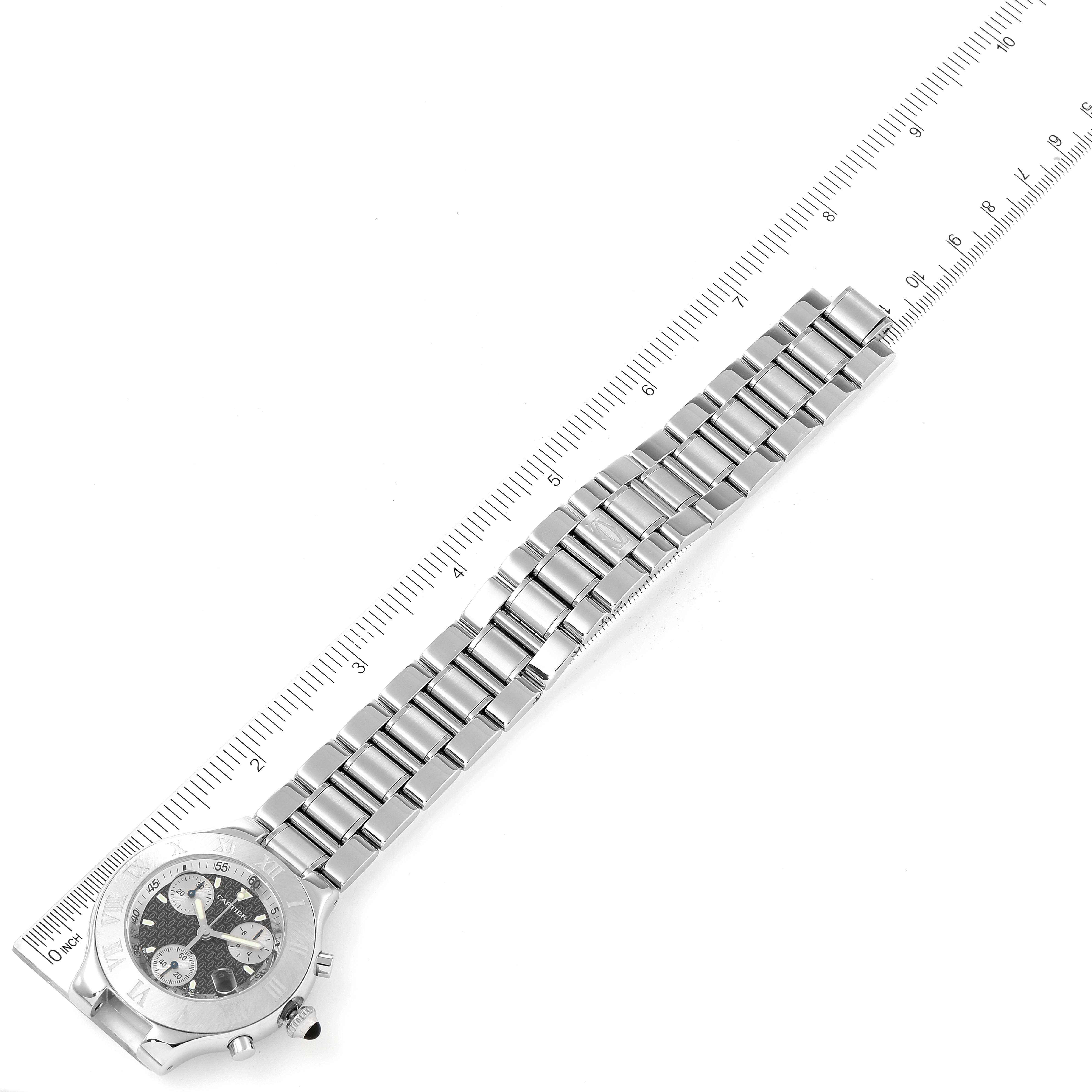 The image shows the Must 21 Chronoscaph watch by Cartier from an overhead angle, highlighting its face, bezel, and metal strap alongside a ruler for scale.