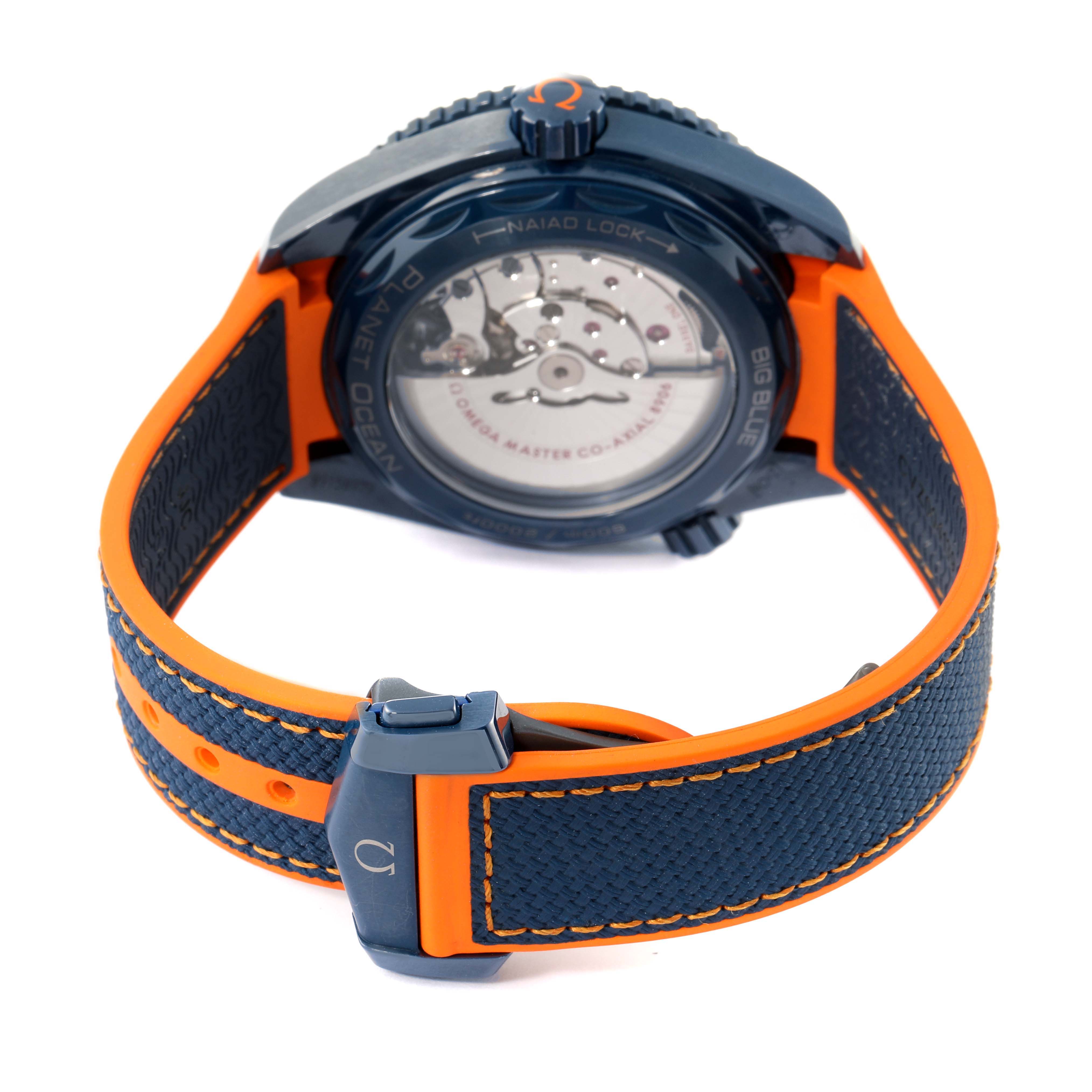 The image shows the back view of the Omega Planet Ocean 215.92.46.22.03.001 Men's Stainless Steel Blue Dial 215.92.46.22.03.001 Men's Stainless Steel Blue Dial watch, focusing on its case, movement, and blue and orange strap.