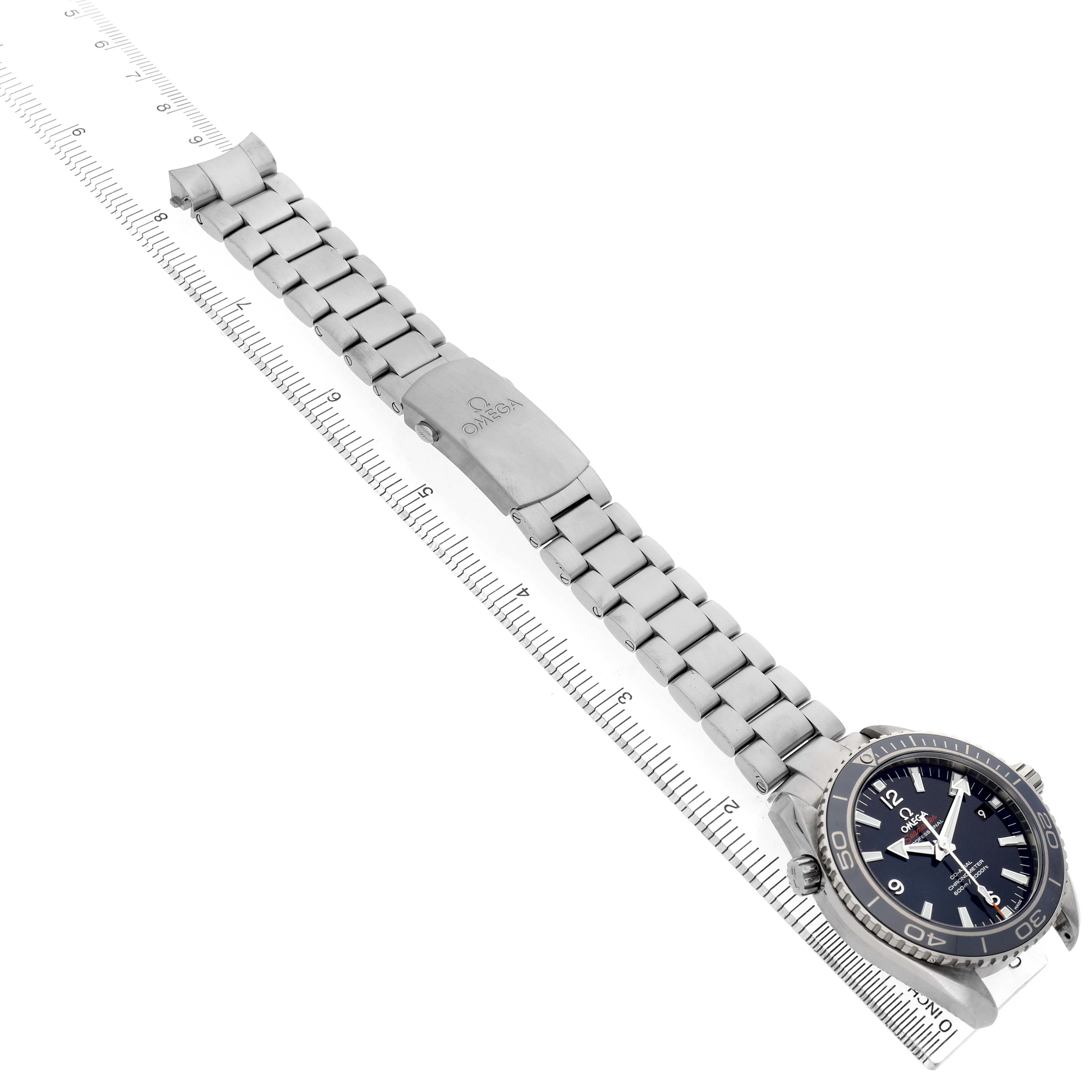 The Omega Seamaster 232.90.42.21.03.001 Men's Titanium Blue Dial watch is shown at a slight angle, highlighting the face, bezel, and metal bracelet laid along a ruler.