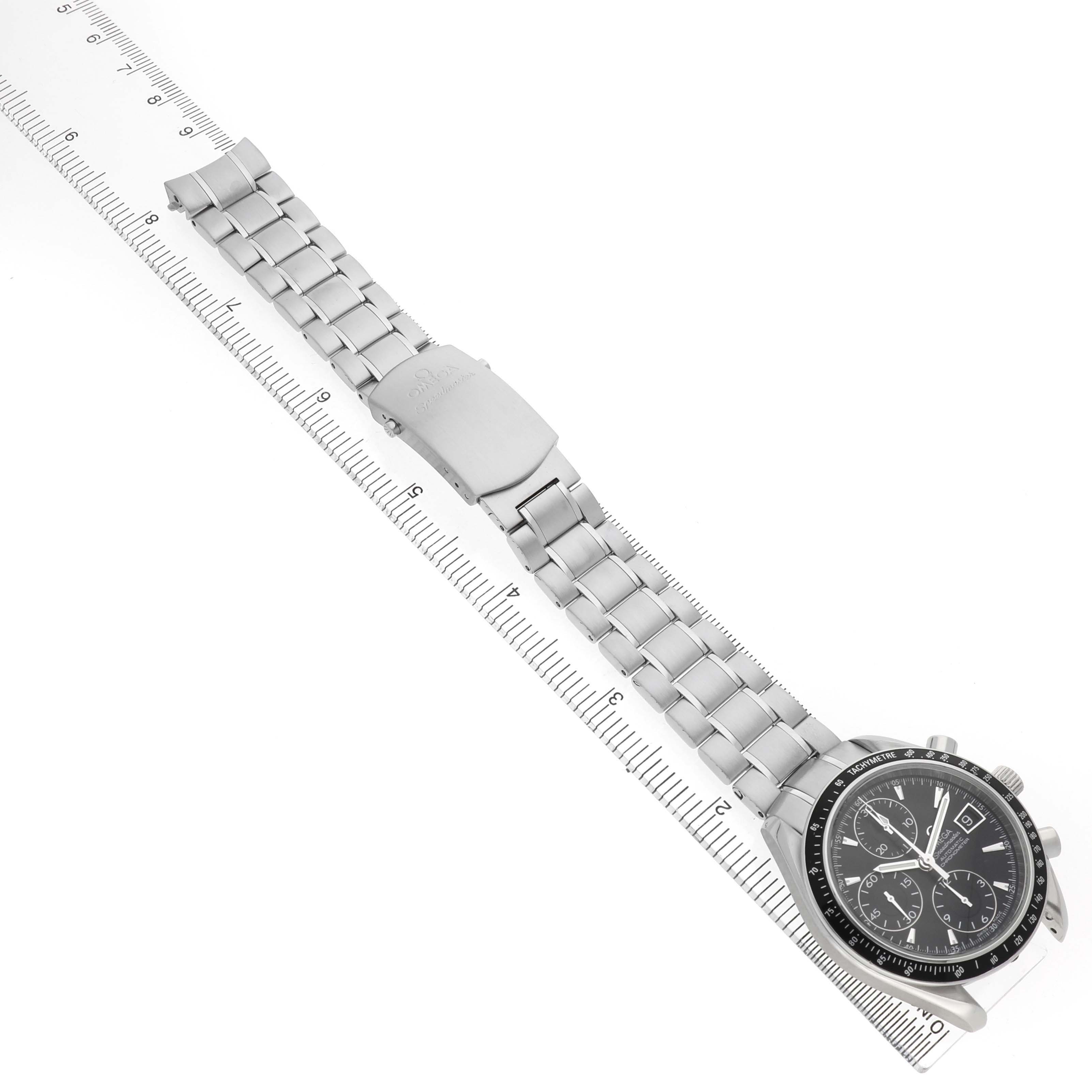 The Omega Speedmaster 3210.50.00 Men's Stainless Steel Black Dial watch is shown from an angled top view, featuring the bracelet and clasp placed alongside a ruler.