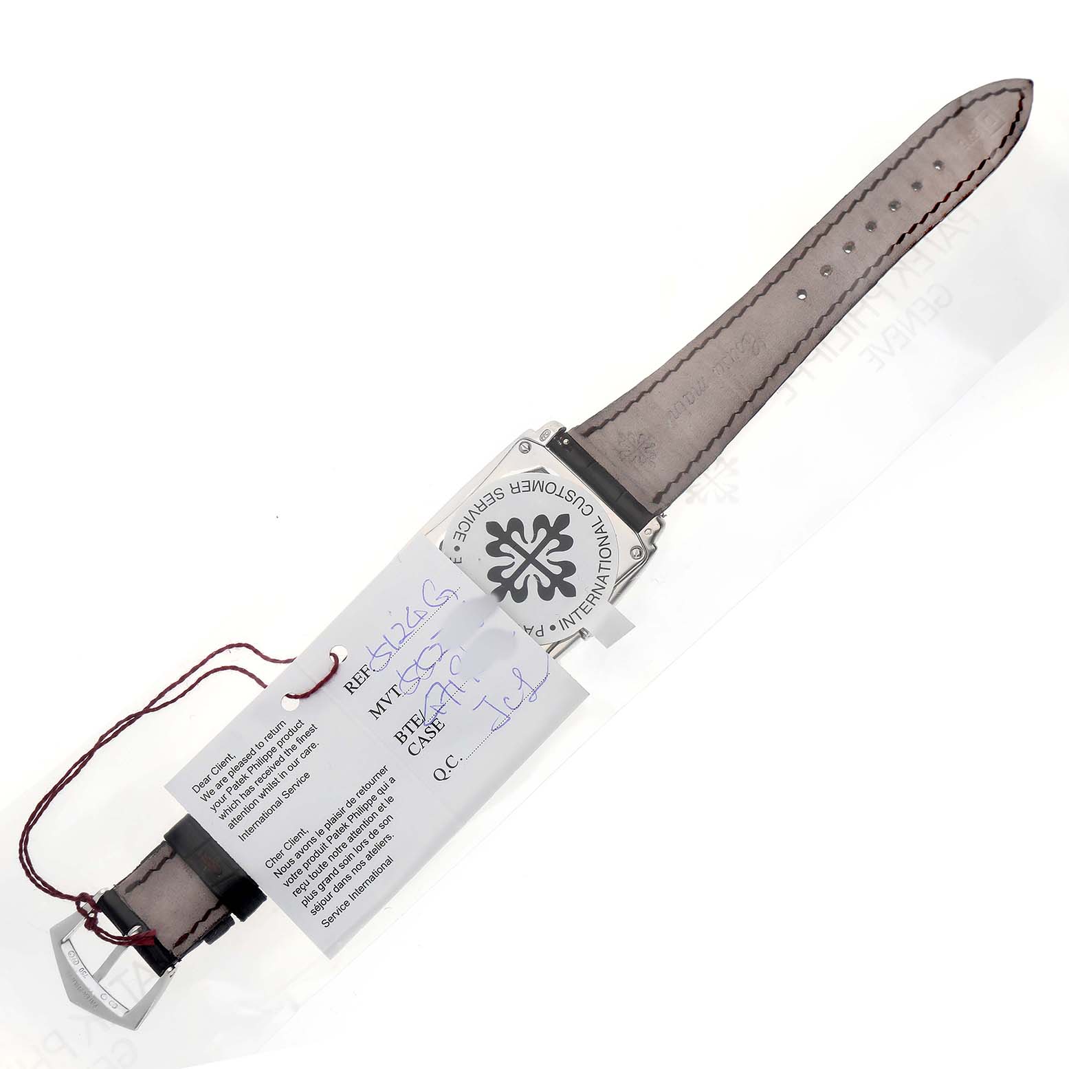 The Patek Philippe Gondolo 5124G-001 Men's White Gold Red Dial watch is shown from the back, highlighting the case back and strap with attached tags.