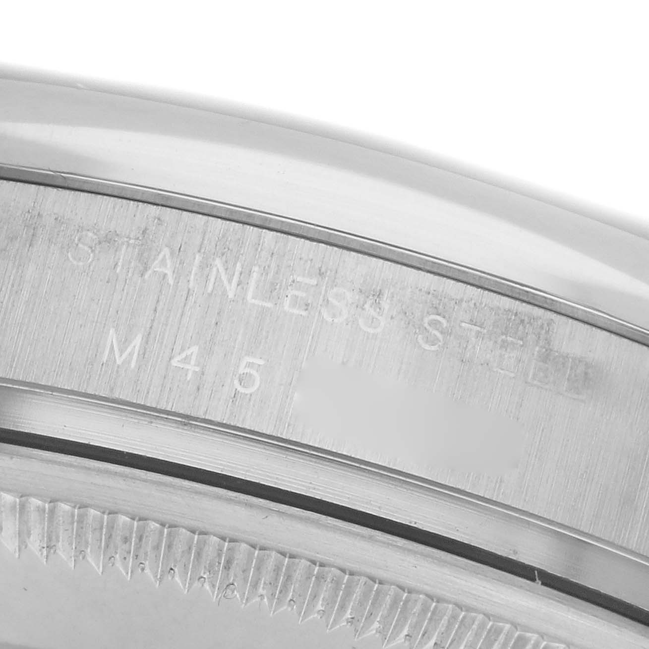 The image shows a close-up of the stainless steel casing on a Rolex Air-King 114200 Men
s Stainless Steel Silver Dial 114200 Men
s Stainless Steel Silver Dial, focusing on the engraved text.