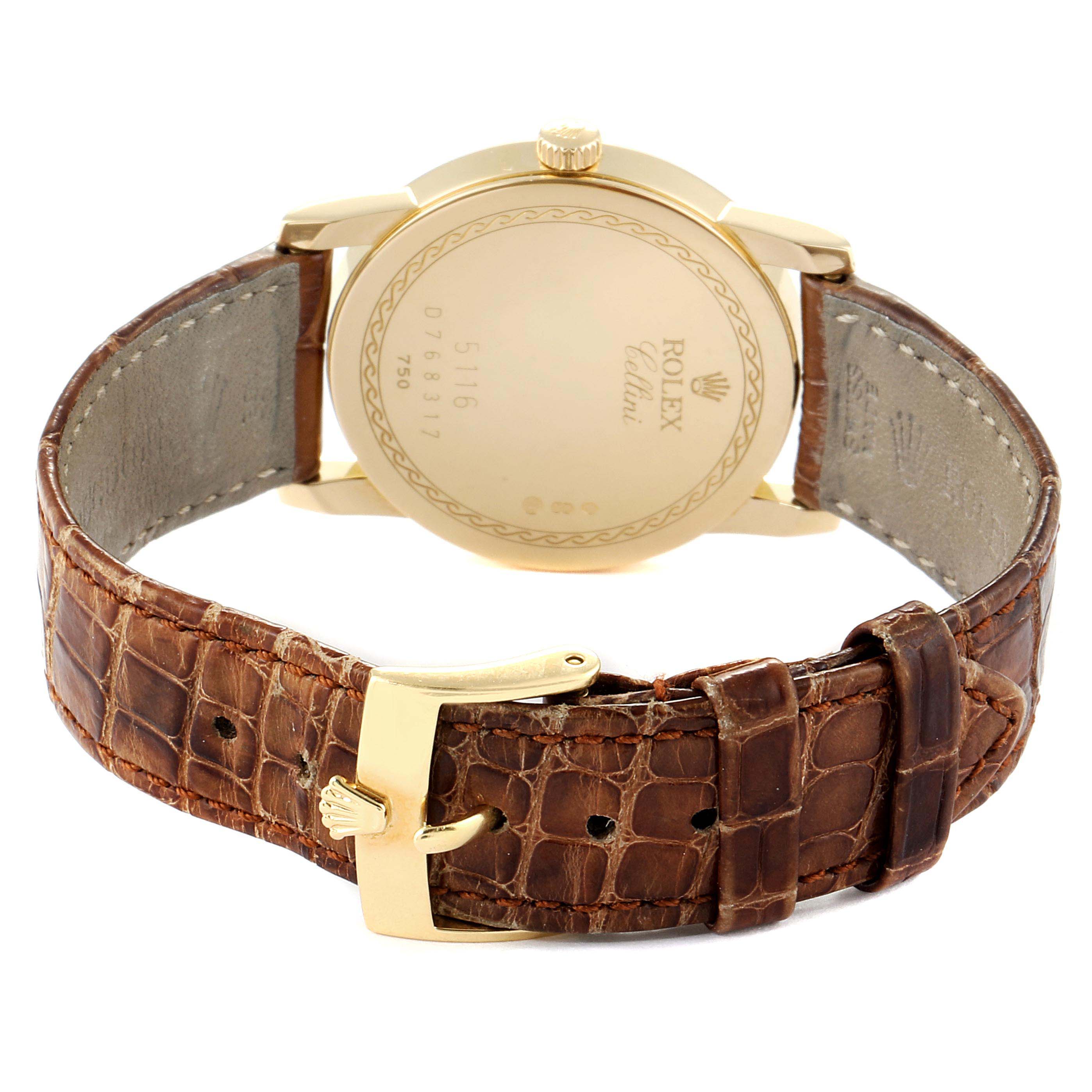 The image shows the back view of a Rolex Cellini 5116 Men's Yellow Gold Black Dial 5116 Men's Yellow Gold Black Dial watch, displaying its gold case back, crown, and brown leather strap with a gold buckle.
