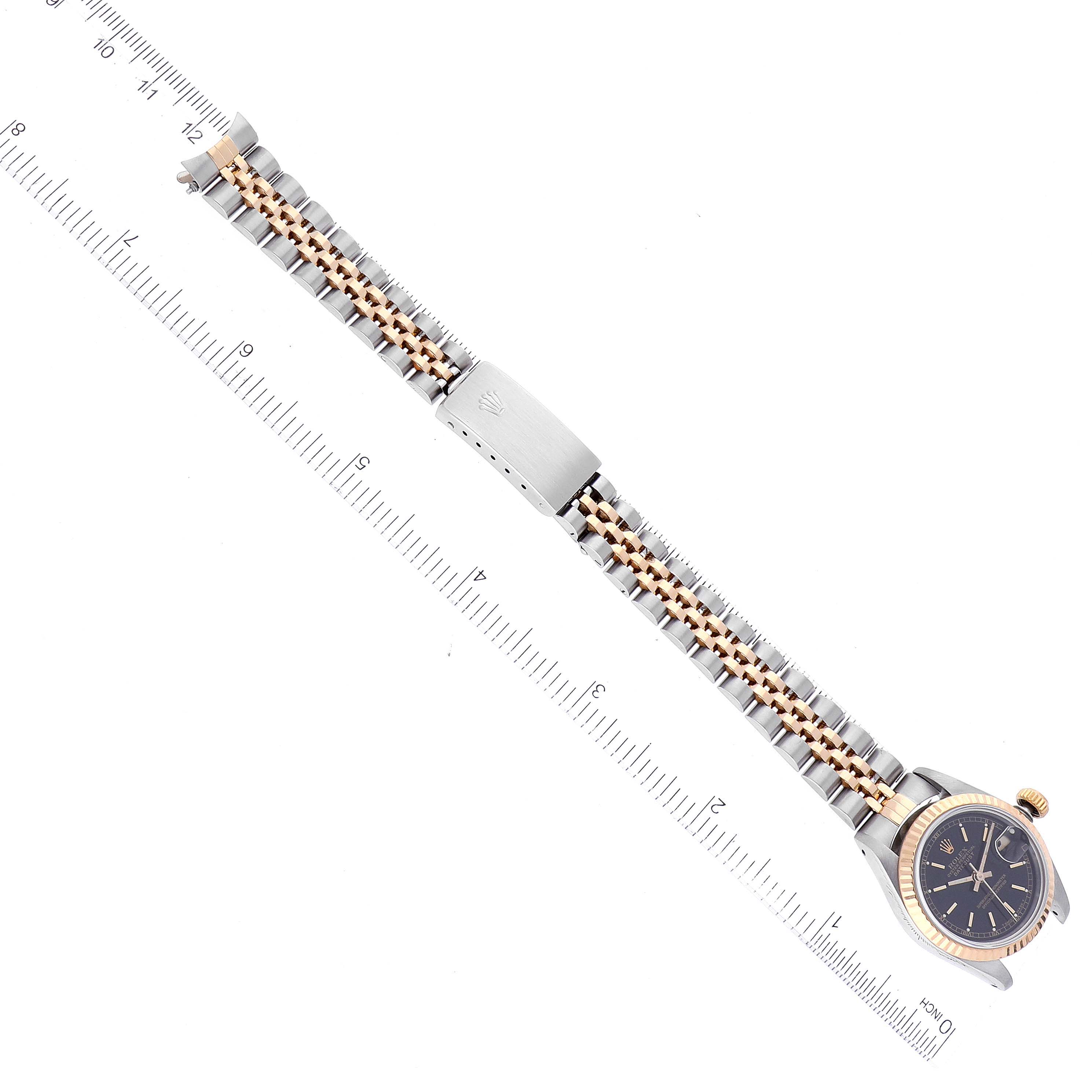 The image shows a Rolex Datejust 69173 Women's Steel and Gold (two tone) Black Dial 69173 Women's Steel and Gold (two tone) Black Dial watch laid flat with its two-tone bracelet and clasp, beside a ruler for scale.