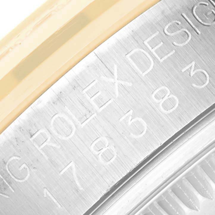 The image shows an angled close-up of the engraved bezel of the Rolex Datejust watch.