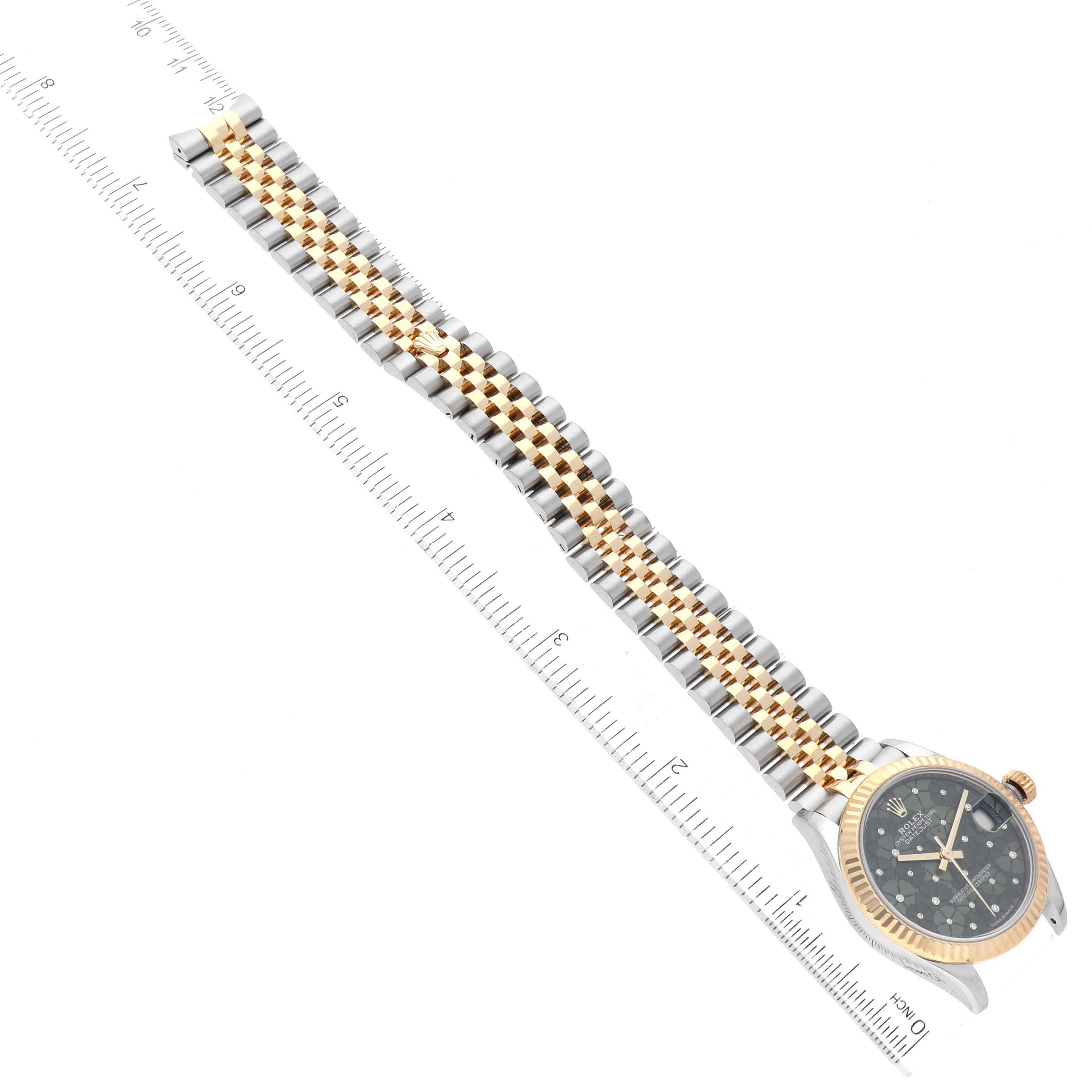 The image shows a top-down view of a Rolex Mid-Size 278273 Women's Steel and Gold (two tone) Green Dial 278273 Women's Steel and Gold (two tone) Green Dial model watch, including its face, bezel, and bracelet, next to a ruler.