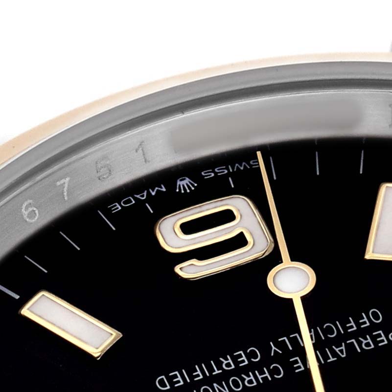 The image shows a close-up of the Rolex Explorer 124273 Men's Steel and Gold (two tone) Black Dial's dial, highlighting the number 9, part of the hands, and “SWISS MADE” text.