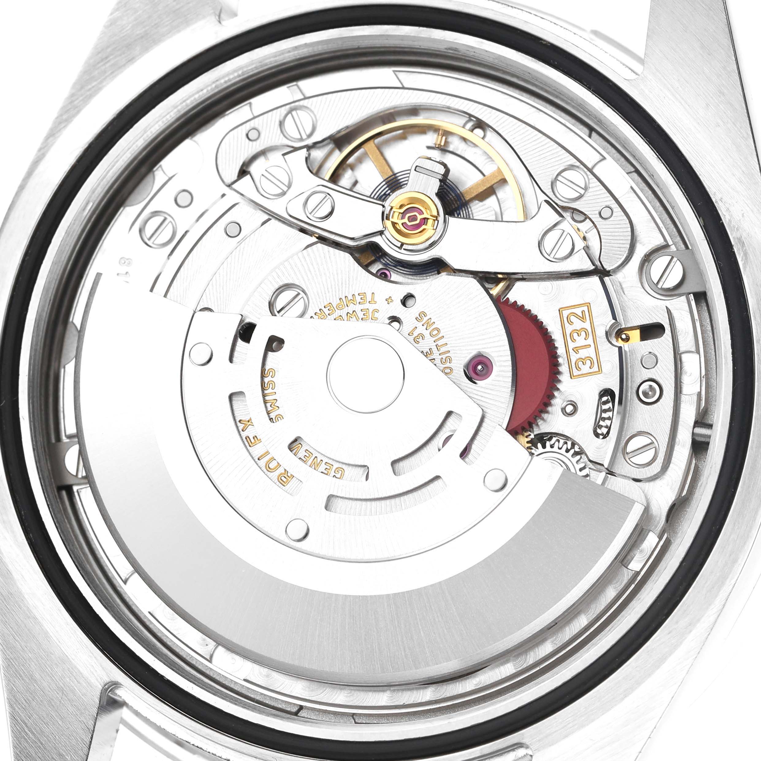 The image shows the movement of a Rolex Oyster Perpetual 114300 Men's Stainless Steel Black Dial watch from the back, highlighting its inner mechanics and rotor.