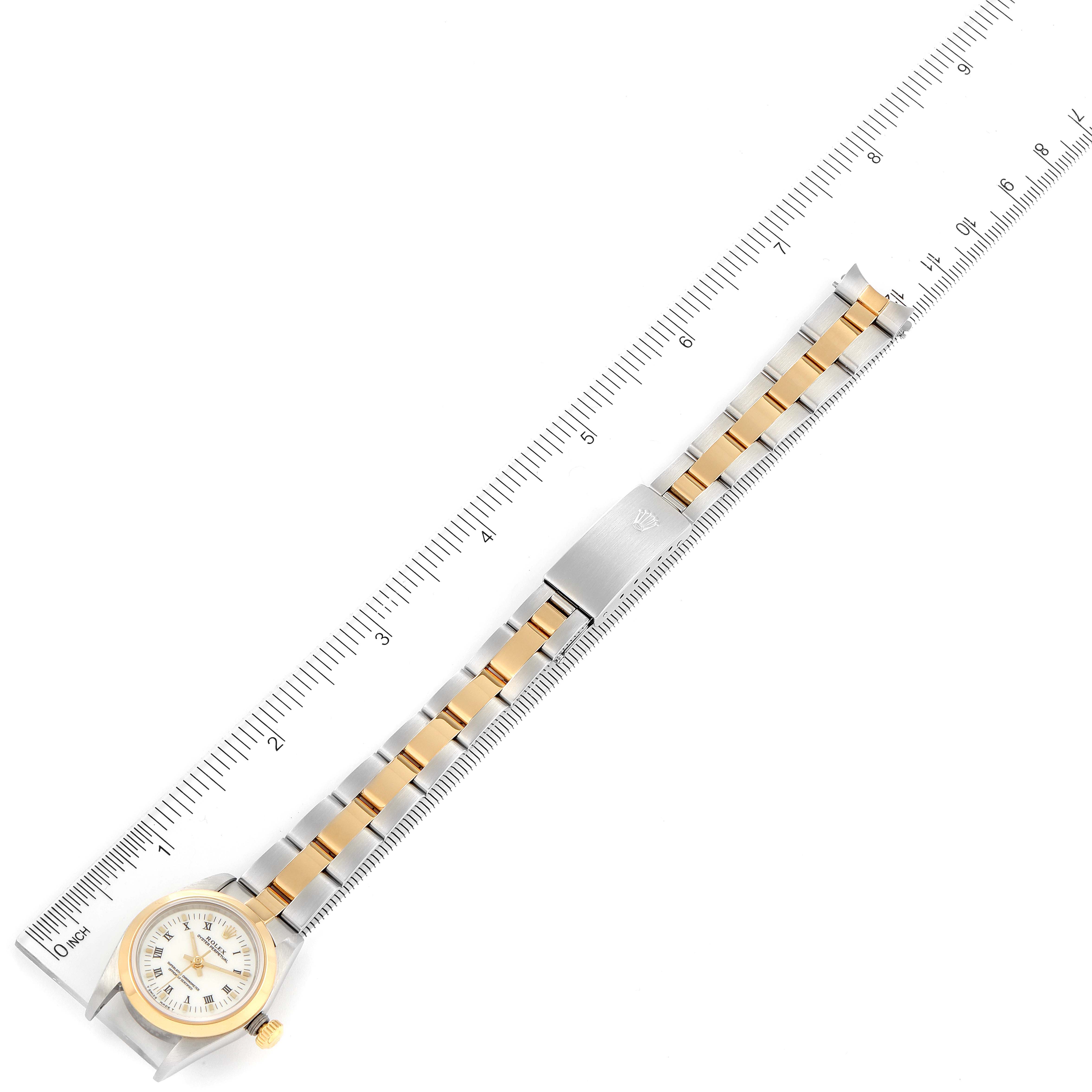 The image shows a top-down view of a Rolex Oyster Perpetual 76183 Women
s Steel and Gold (two tone) White Dial 76183 Women
s Steel and Gold (two tone) White Dial watch with a metal ruler measuring its length.