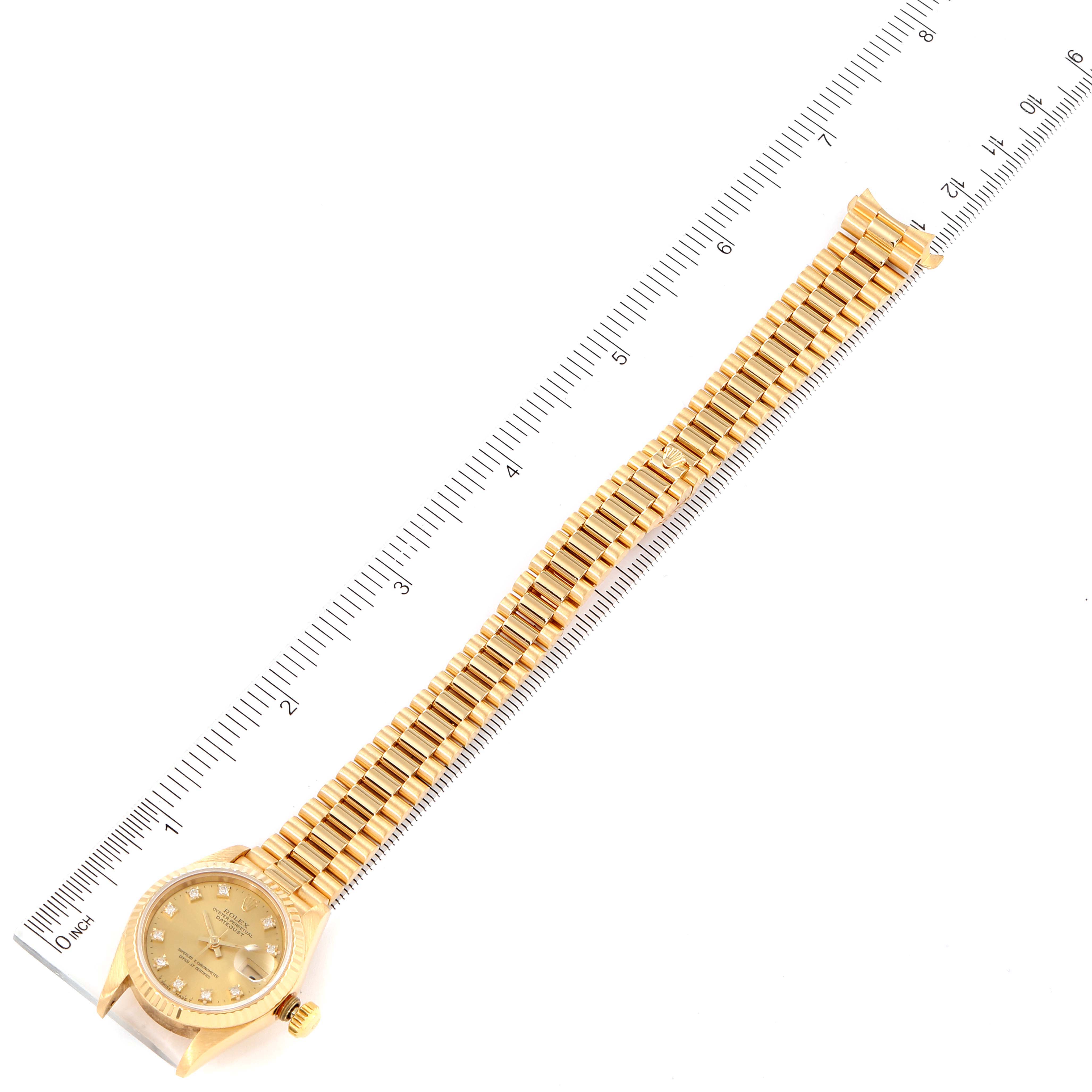 The image shows a full frontal view of a Rolex President 69178 Women
s Yellow Gold Champagne Dial 69178 Women
s Yellow Gold Champagne Dial model watch, including the face and the complete bracelet, laid next to a ruler.