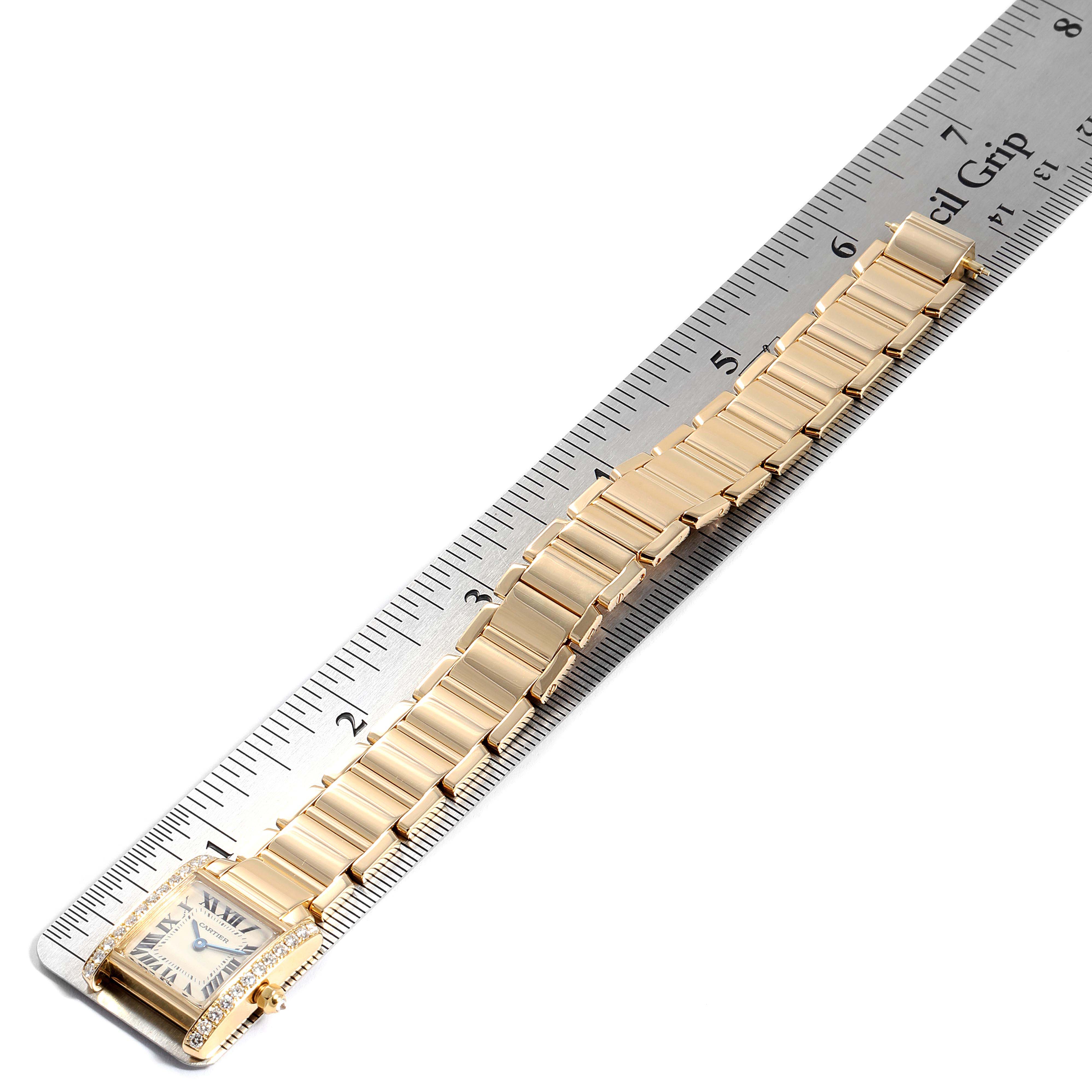 The image shows a Cartier Tank Francaise WE1001R8 Women's Yellow Gold Silver Dial WE1001R8 Women's Yellow Gold Silver Dial watch laid next to a ruler to display its entire length, including the face and bracelet.