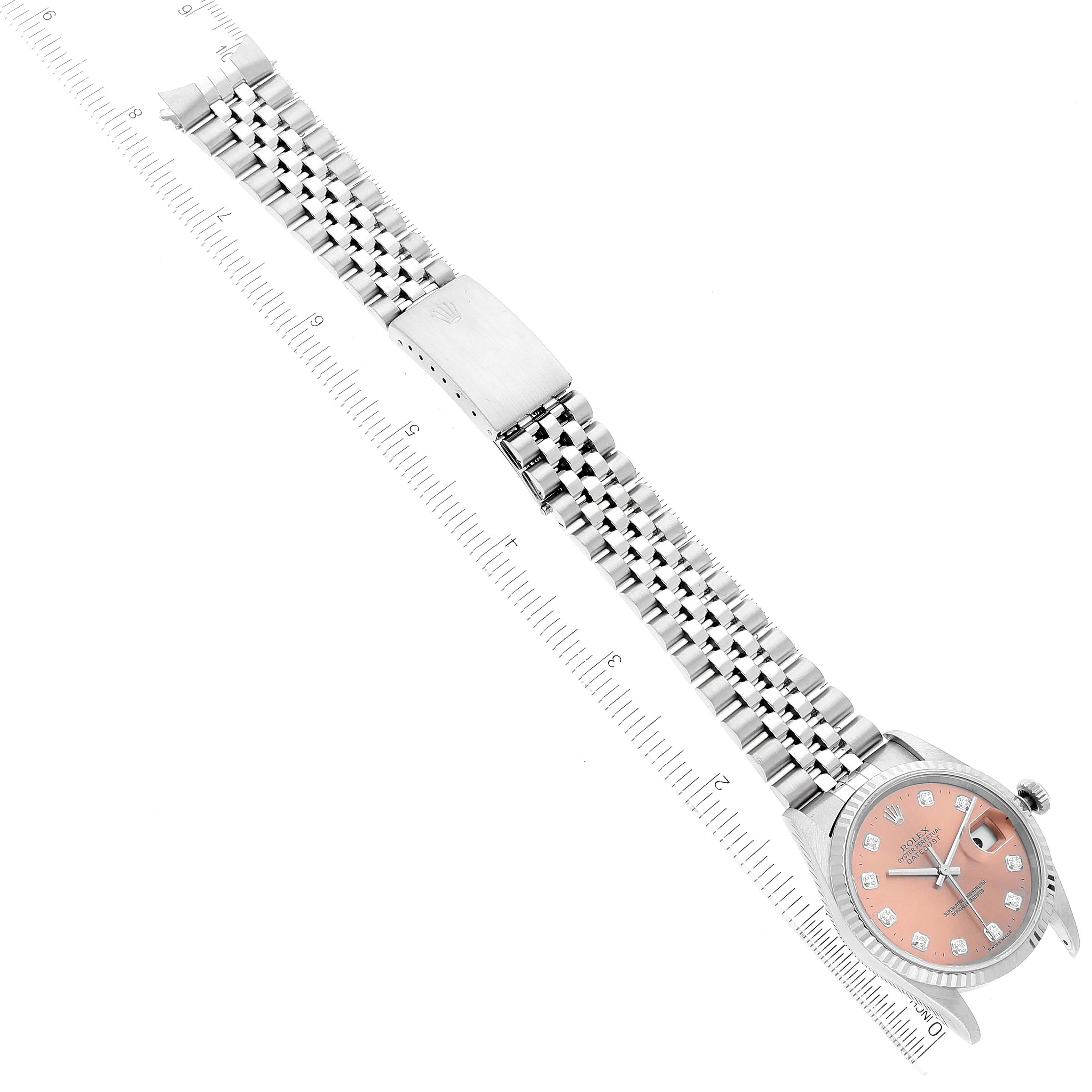 The Rolex Datejust 16234 Men
s Stainless Steel Pink Dial 16234 Men
s Stainless Steel Pink Dial watch is shown at an angle, displaying its face, bezel, crown, and full bracelet on a ruler.