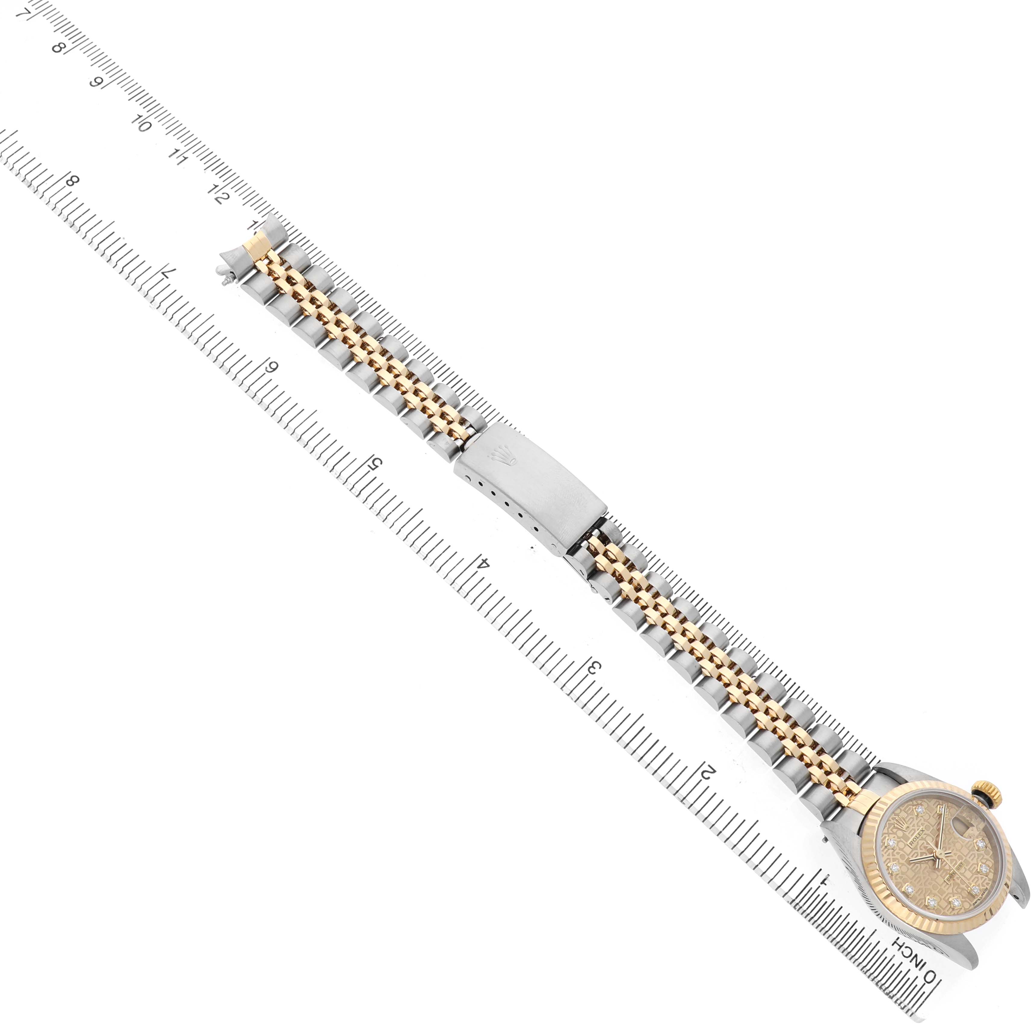 The Rolex Datejust 79173 Women's Steel and Gold (two tone) Champagne Dial is shown from a top-down angle, displaying the face, bracelet, and clasp alongside a ruler for scale.