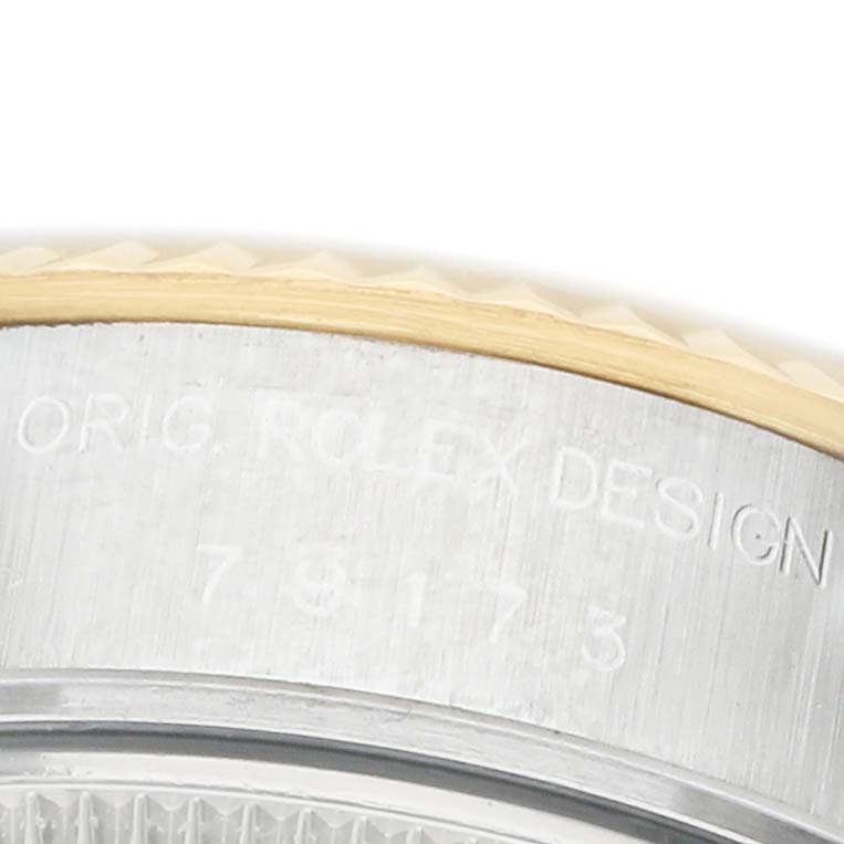 The image shows a close-up of the edge of the Rolex Datejust 79173 Women's Steel and Gold (two tone) Champagne Dial's case and bezel, highlighting the engraved design details.