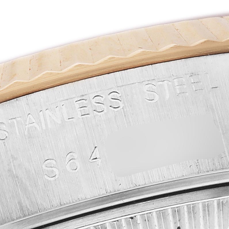 The image shows a close-up of the Rolex Datejust 69173 Women
s Steel and Gold (two tone) Champagne Dial 69173 Women
s Steel and Gold (two tone) Champagne Dial watch
s fluted bezel and engraved stainless steel case.