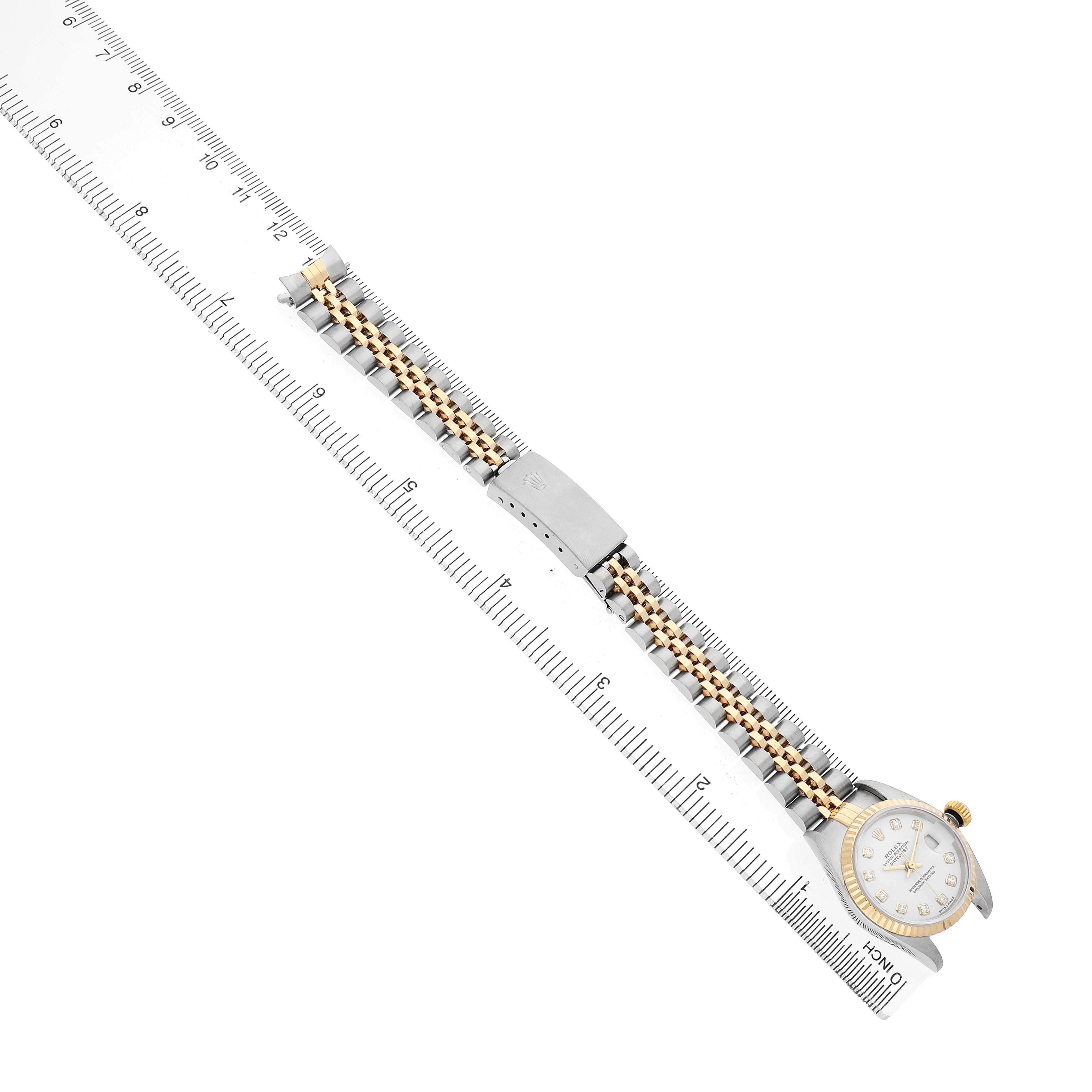 The Rolex Datejust 79173 Women's Steel and Gold (two tone) White Dial watch is shown at an angle with its face, bezel, bracelet, and clasp visible alongside a ruler.