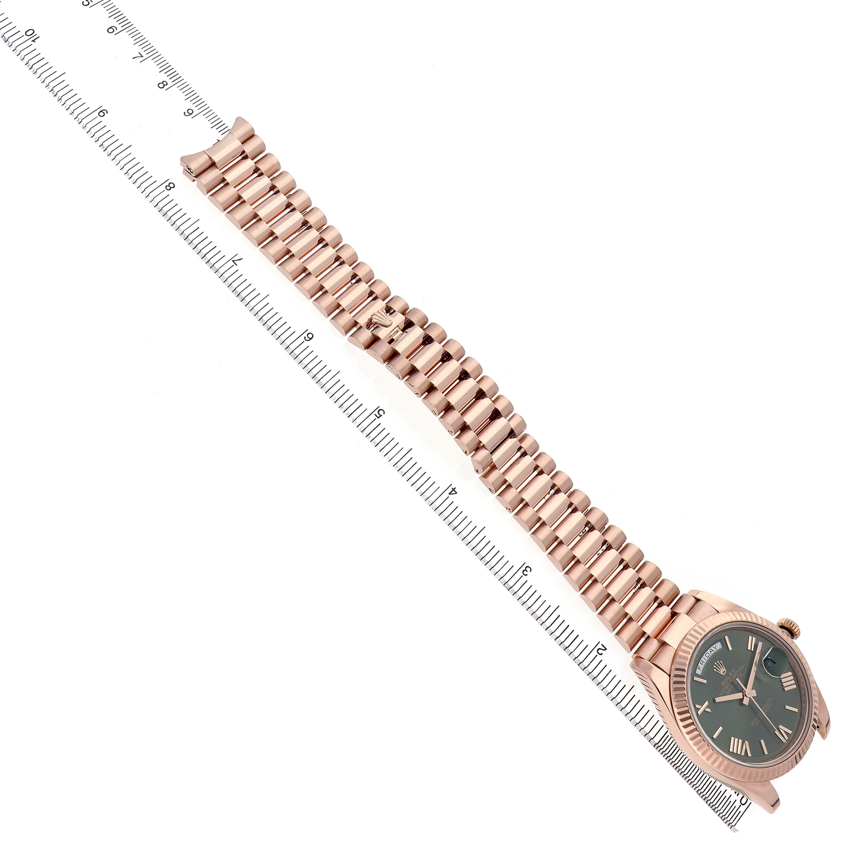 The Rolex President 228235 Men's Rose Gold Green Dial model is shown at a top-down angle, displaying the watch face and full bracelet alongside a ruler.