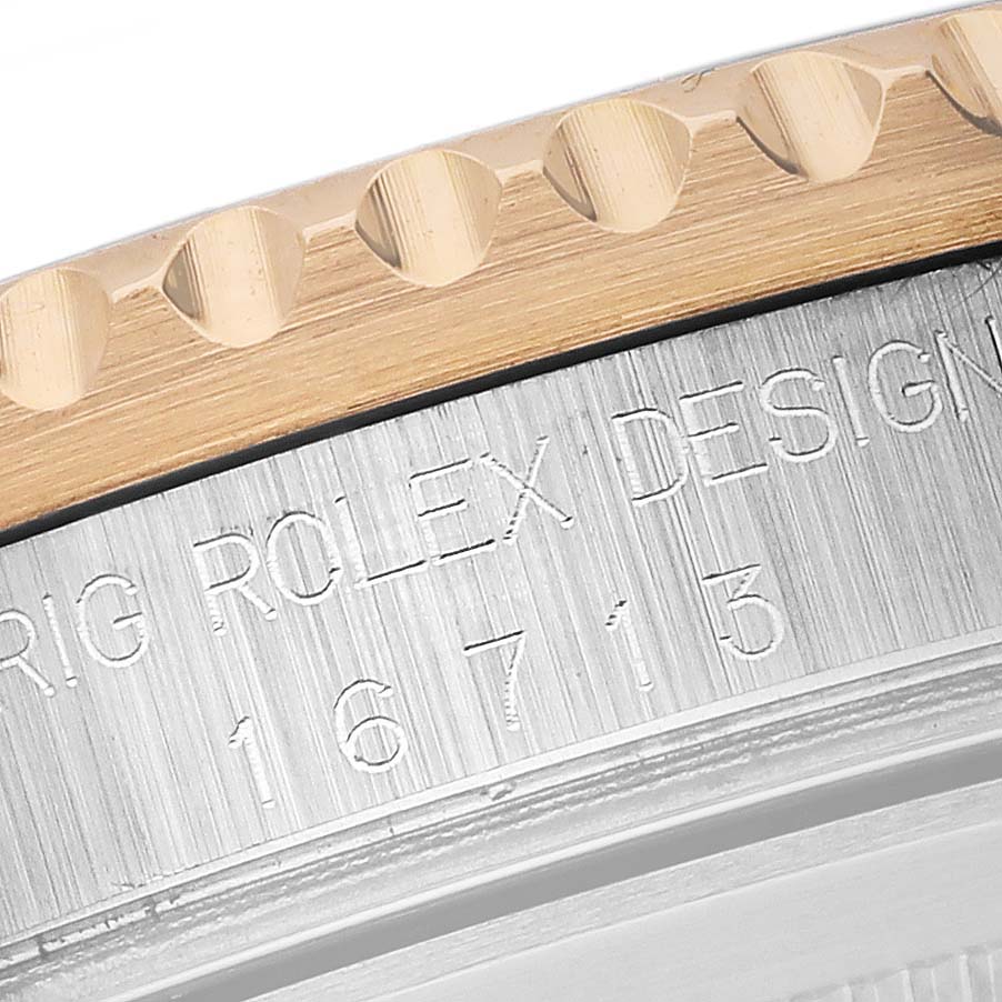 The image shows a close-up of the bezel and engraved case side of a Rolex GMT-Master 16713 Men
s Steel and Gold (two tone) Brown Dial 16713 Men
s Steel and Gold (two tone) Brown Dial watch.