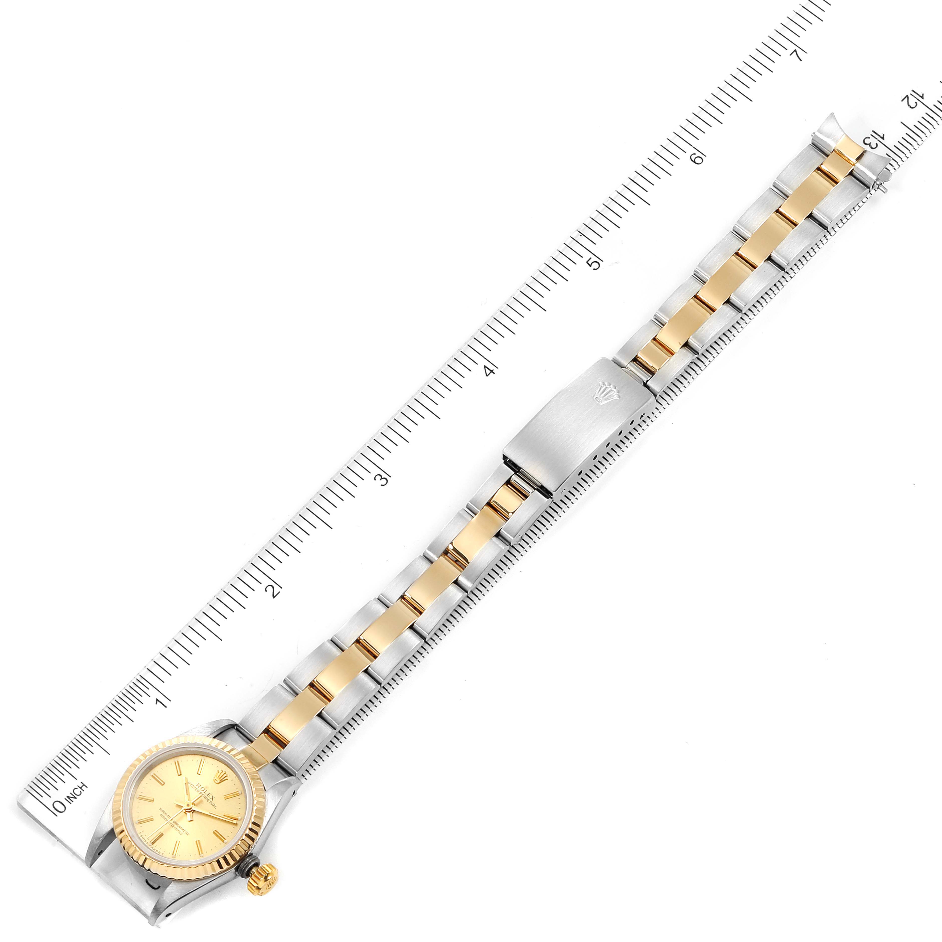 This Rolex Oyster Perpetual 67193 Women
s Steel and Gold (two tone) Champagne Dial 67193 Women
s Steel and Gold (two tone) Champagne Dial watch is shown from a top-down angle, displaying the entire band and face alongside a ruler.