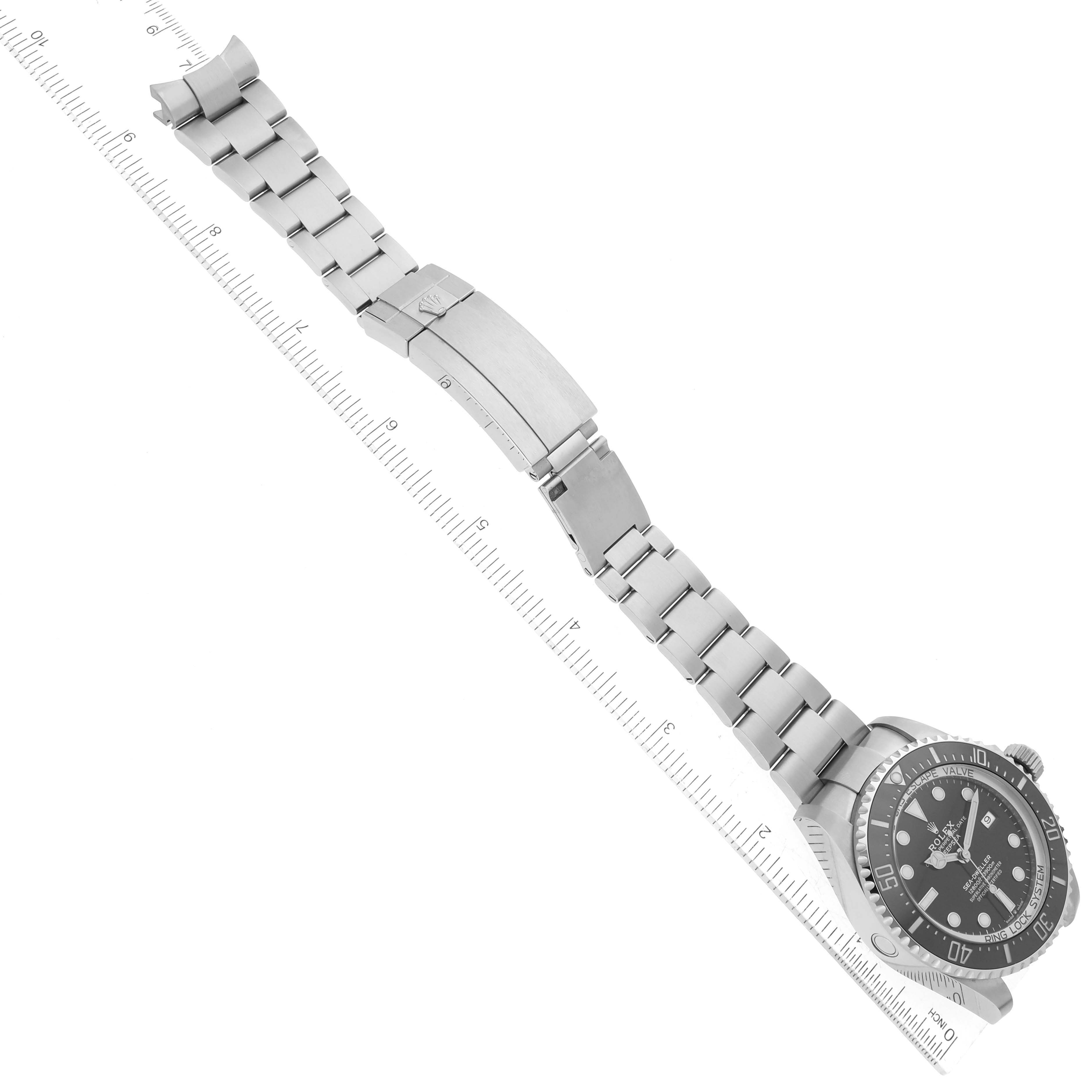 The image shows the Rolex Sea-Dweller 126660 Men
s Stainless Steel Black Dial 126660 Men
s Stainless Steel Black Dial model watch at an angle displaying the face, full bracelet, and clasp beneath a ruler.
