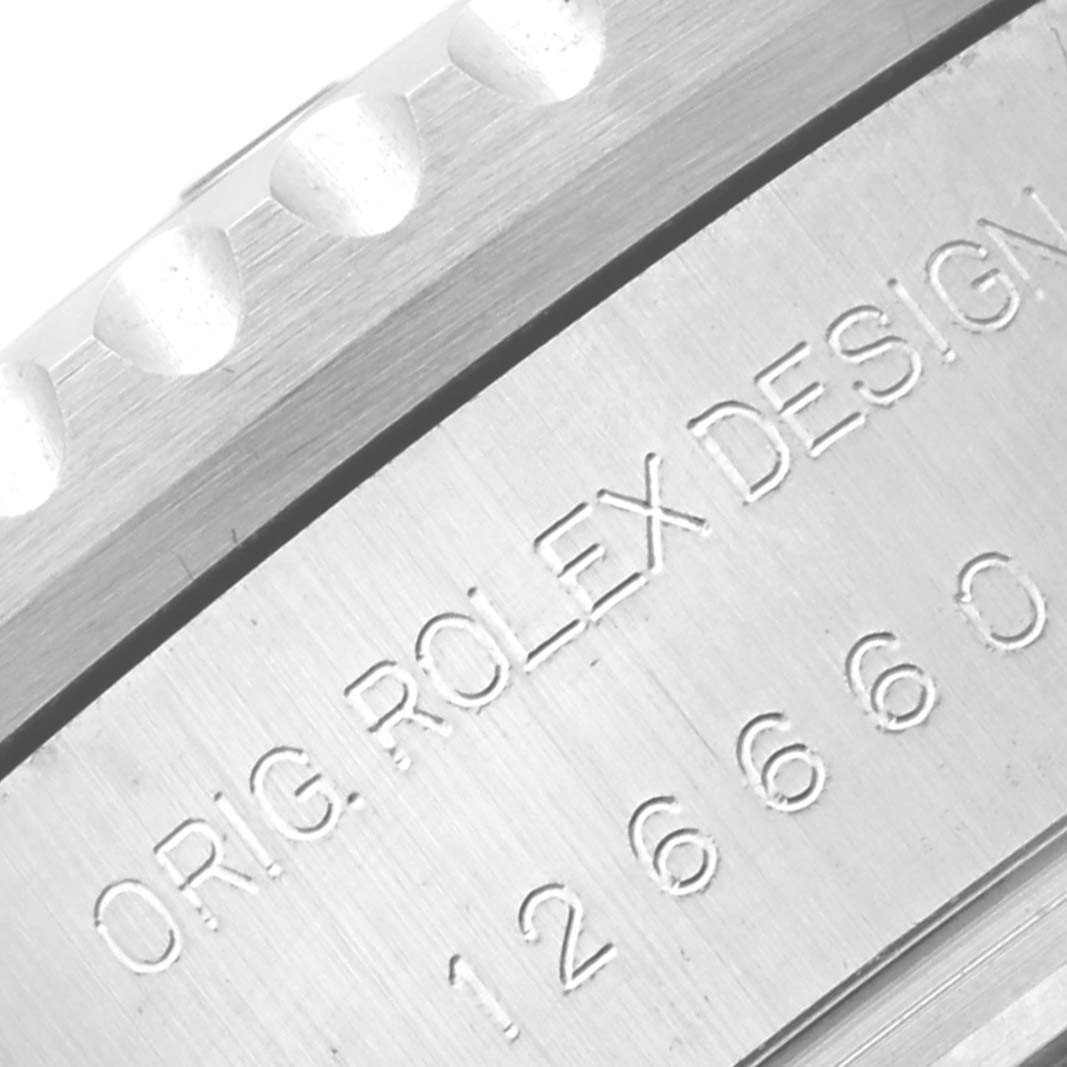 The image shows a close-up of the side of a Rolex Sea-Dweller 126660 Men
s Stainless Steel Black Dial 126660 Men
s Stainless Steel Black Dial watch, revealing part of the serrated bezel and engraved model details.