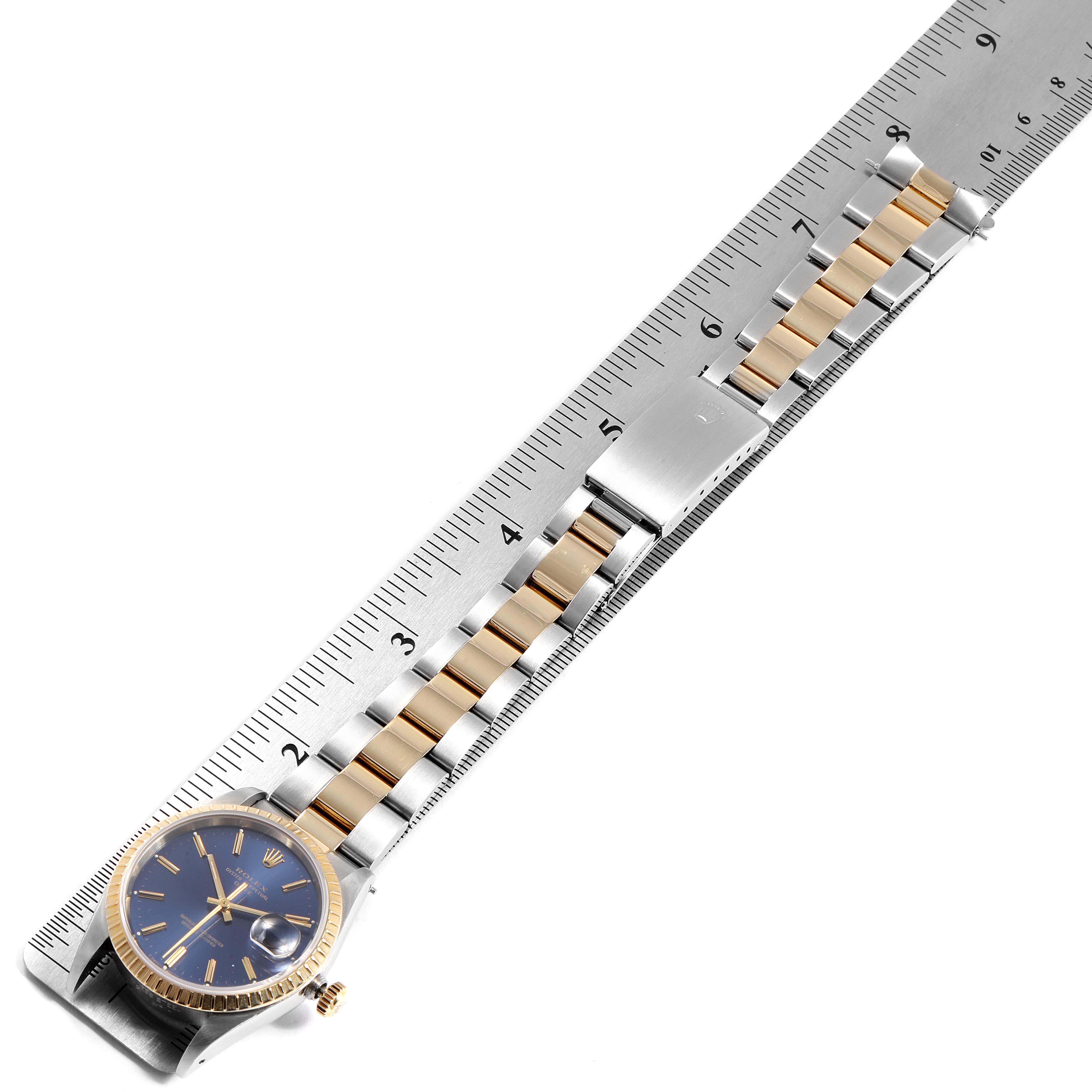 This image shows a top-down view of a Rolex Date 15223 Men's Steel and Gold (two tone) Blue Dial 15223 Men's Steel and Gold (two tone) Blue Dial model watch laid against a ruler, displaying the watch face, bezel, and bracelet.