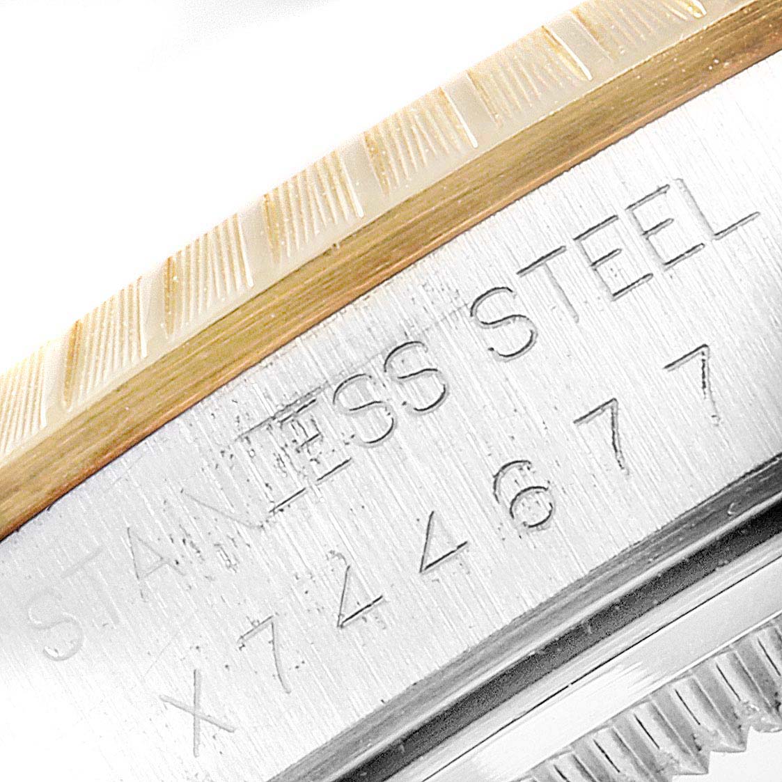 The image shows a close-up of the side of the bezel and case of a Rolex Date 15223 Men's Steel and Gold (two tone) Blue Dial 15223 Men's Steel and Gold (two tone) Blue Dial model watch, displaying the engraving "STAINLESS STEEL" and a serial number.