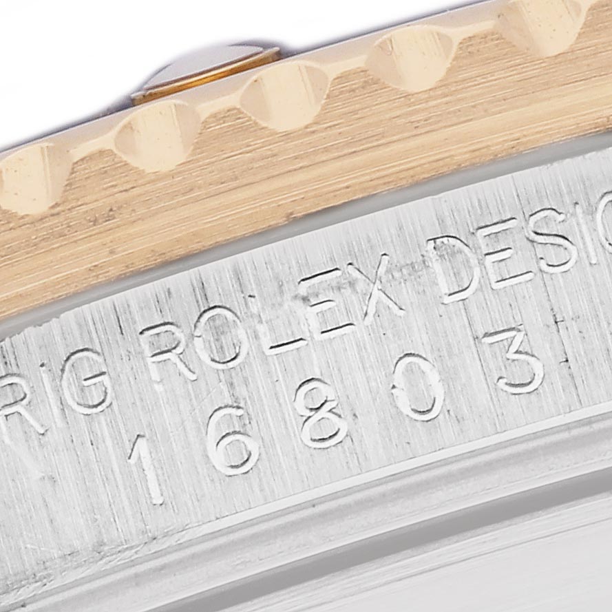 The image shows a close-up of the bezel and engraved detailing on the case side of a Rolex Submariner 16803 Men
s Steel and Gold (two tone) Black Dial 16803 Men
s Steel and Gold (two tone) Black Dial watch.