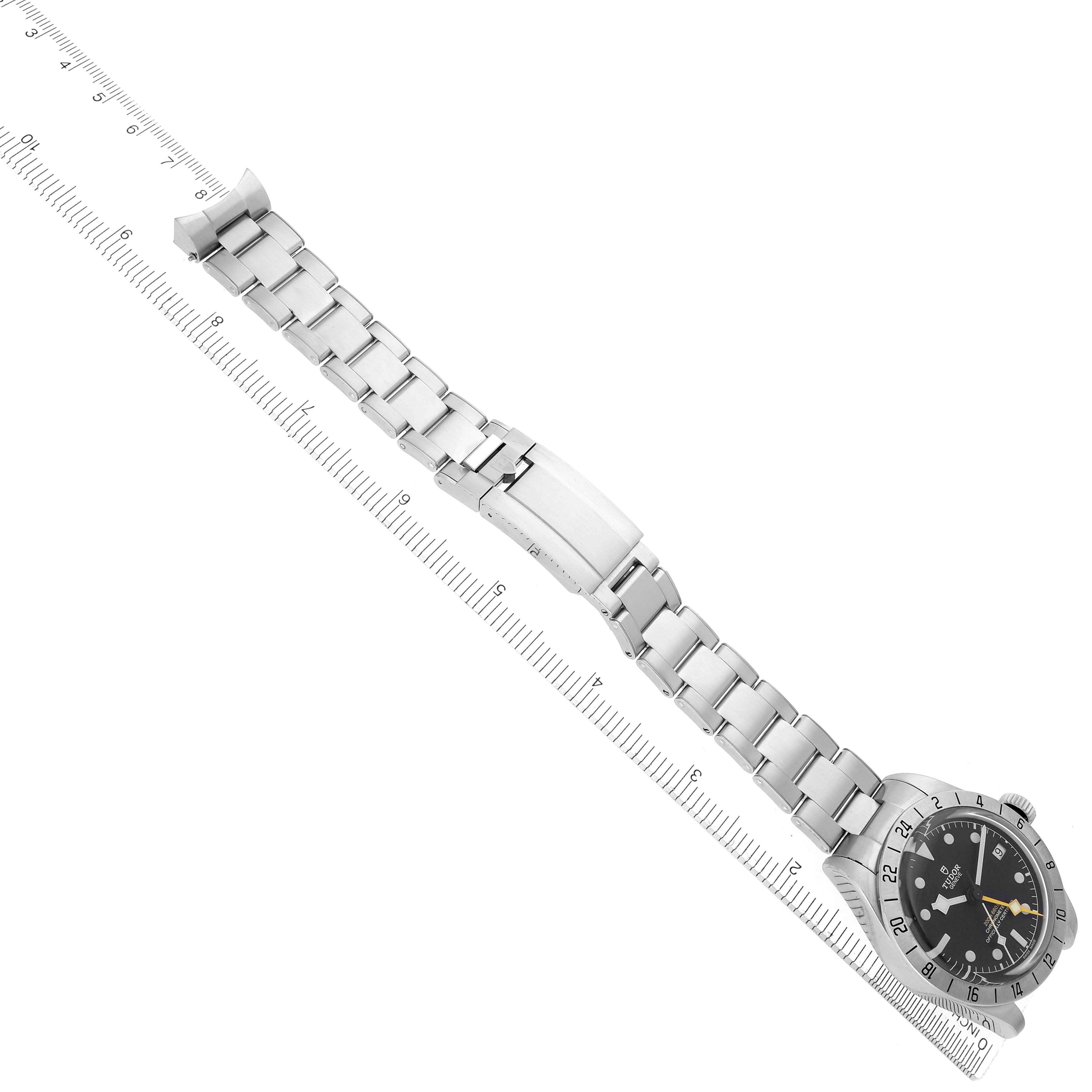 The Tudor Heritage Black Bay 79470 Men
s Stainless Steel Black Dial 79470 Men
s Stainless Steel Black Dial watch is shown at an angle, displaying the face, bezel, bracelet, clasp, and extension along a ruler.