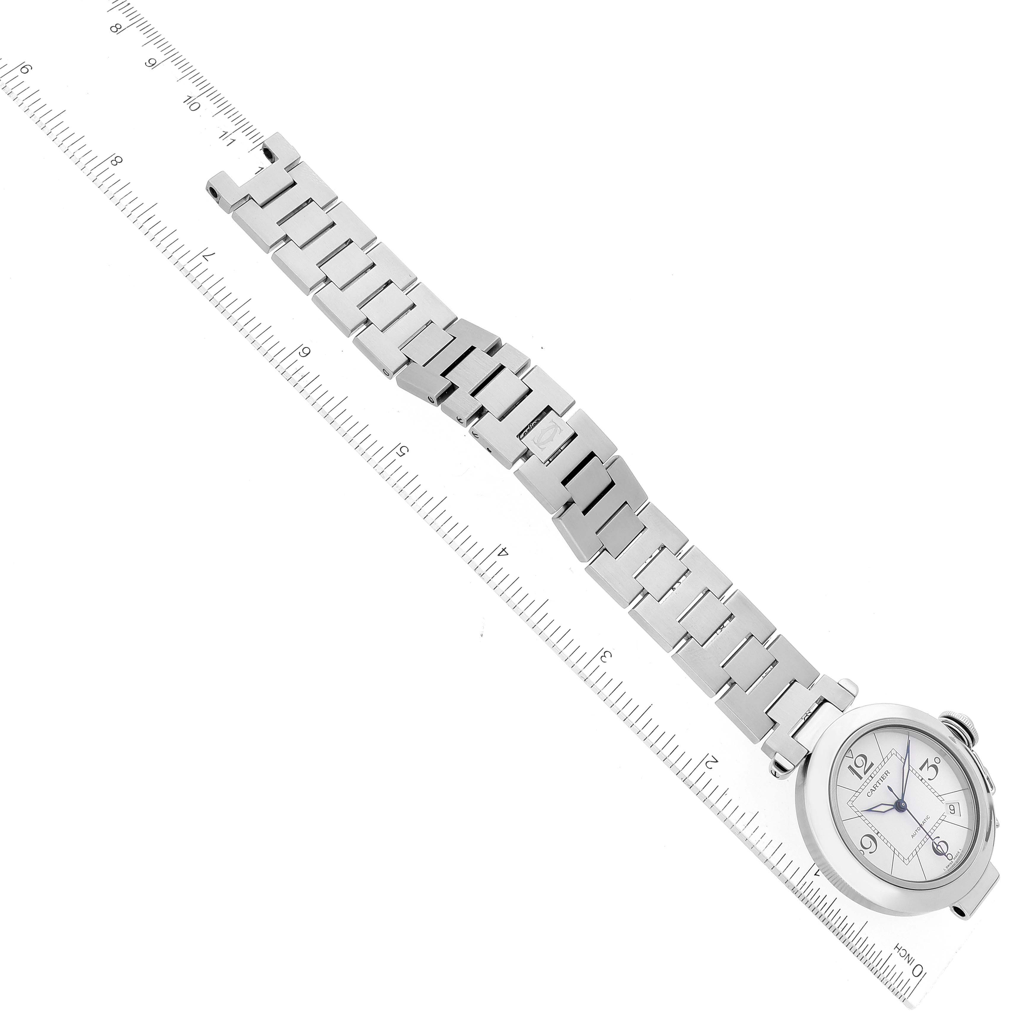 The Cartier Pasha W31074M7 Men's Stainless Steel White Dial W31074M7 Men's Stainless Steel White Dial watch is shown flat with its metal bracelet extended alongside a ruler for scale.