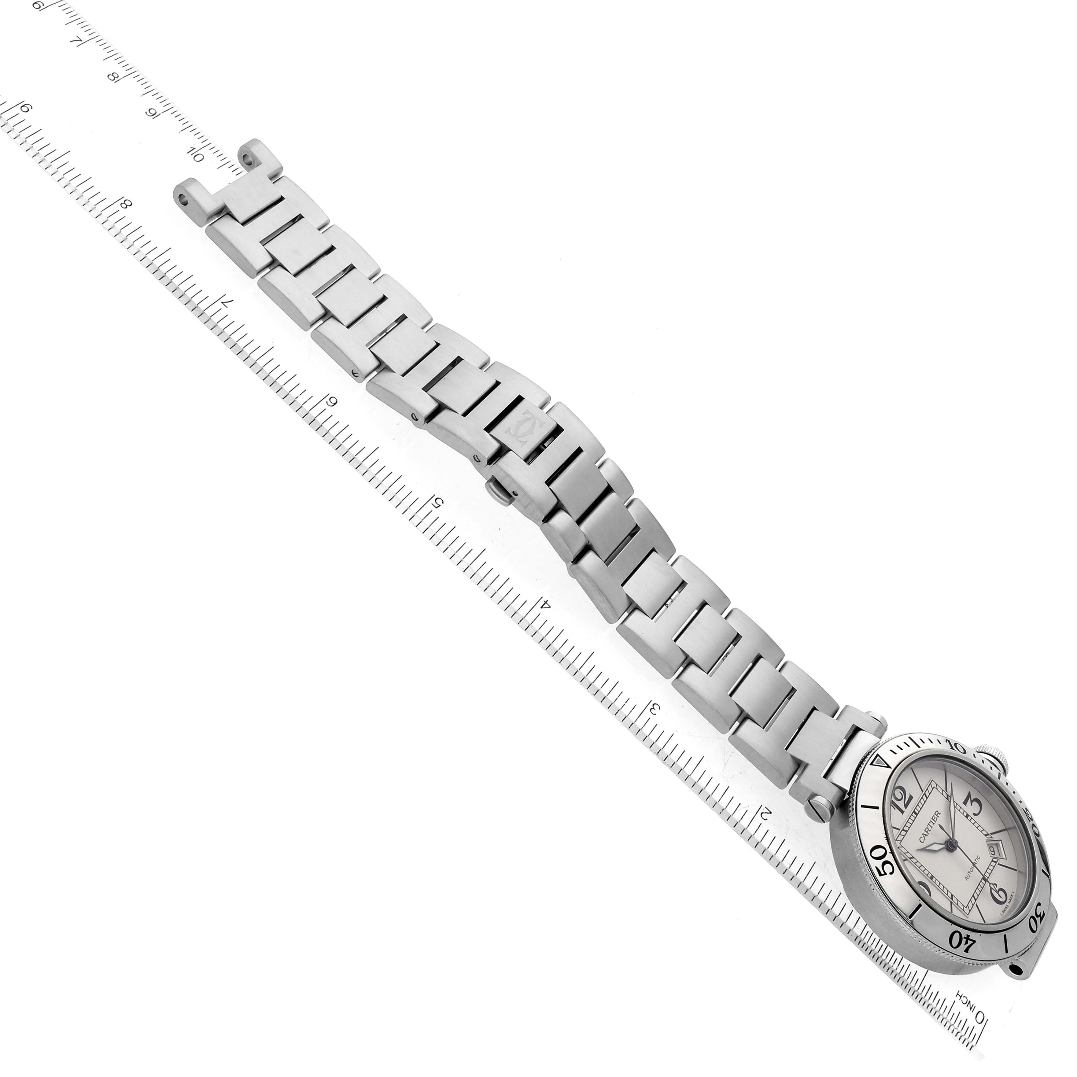 The image shows a side-angle view of a Cartier Pasha W31080M7 Men
s Stainless Steel Silver Dial W31080M7 Men
s Stainless Steel Silver Dial watch with its band, lying next to a ruler for scale.