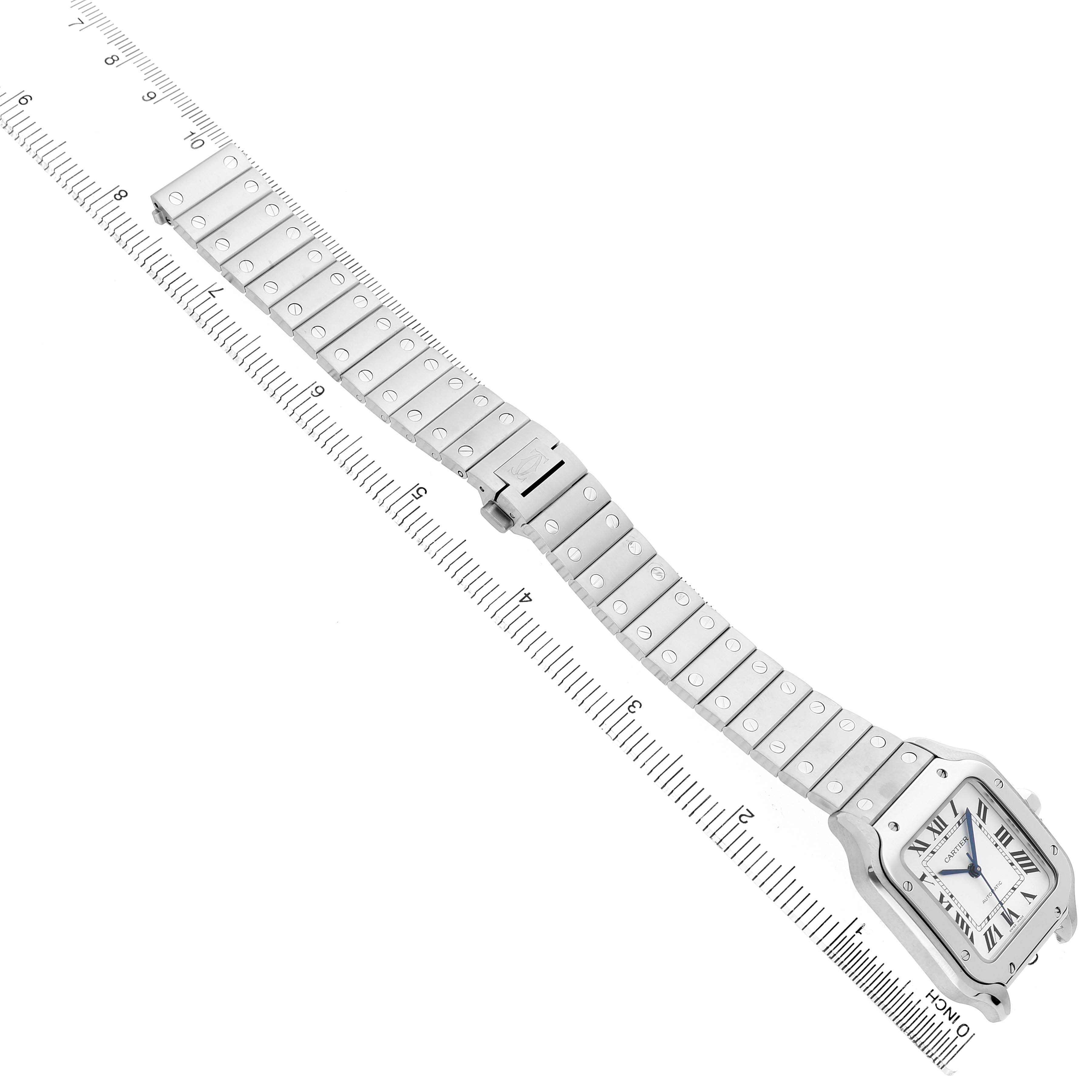 The Cartier Santos WSSA0029 Men's Stainless Steel Silver Dial watch is shown from a top view, highlighting its face and metal bracelet alongside a ruler for scale.