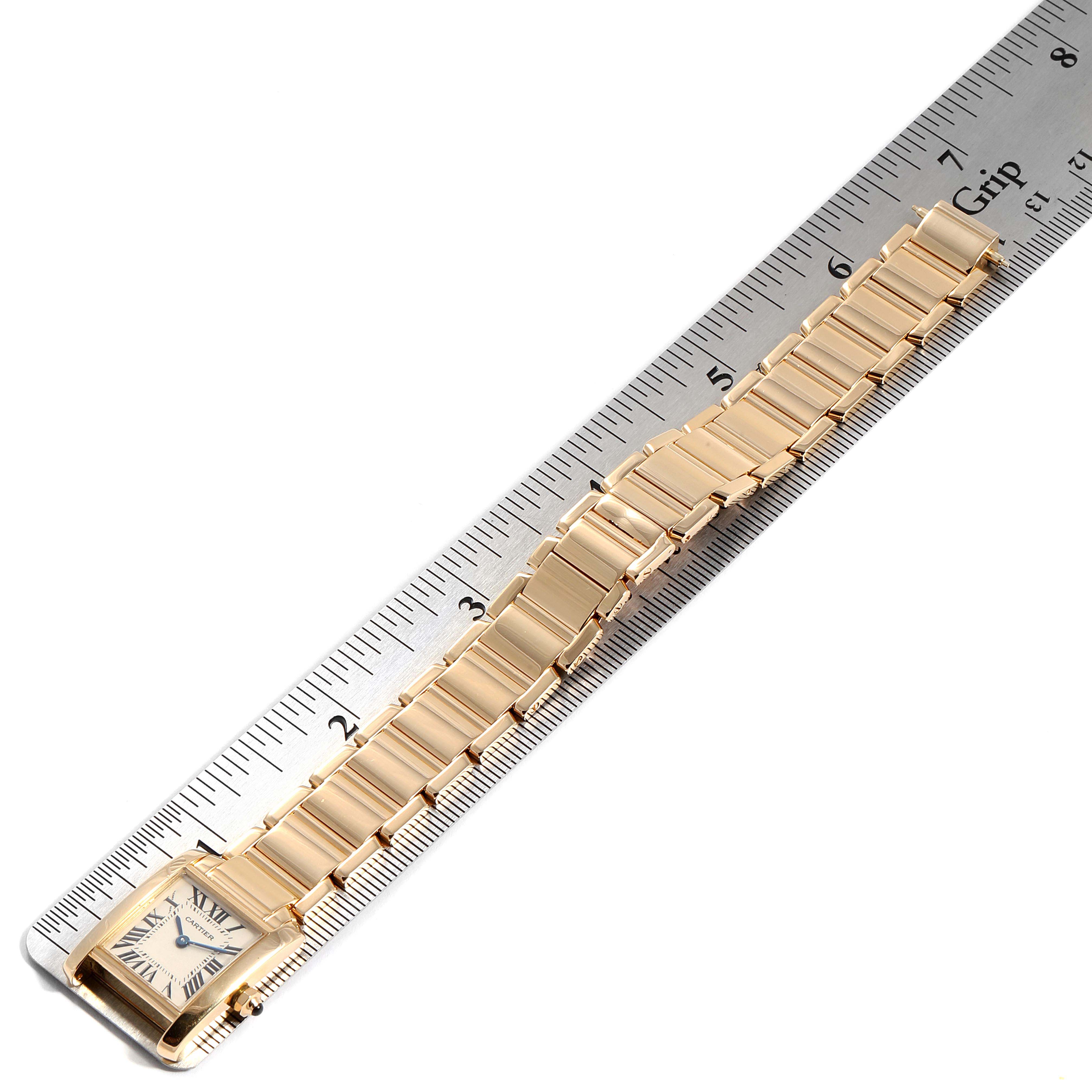 This image shows the Cartier Tank Francaise W50002N2 Women's Yellow Gold Silver Dial W50002N2 Women's Yellow Gold Silver Dial watch laid flat next to a ruler, showcasing the band and face from an overhead angle.