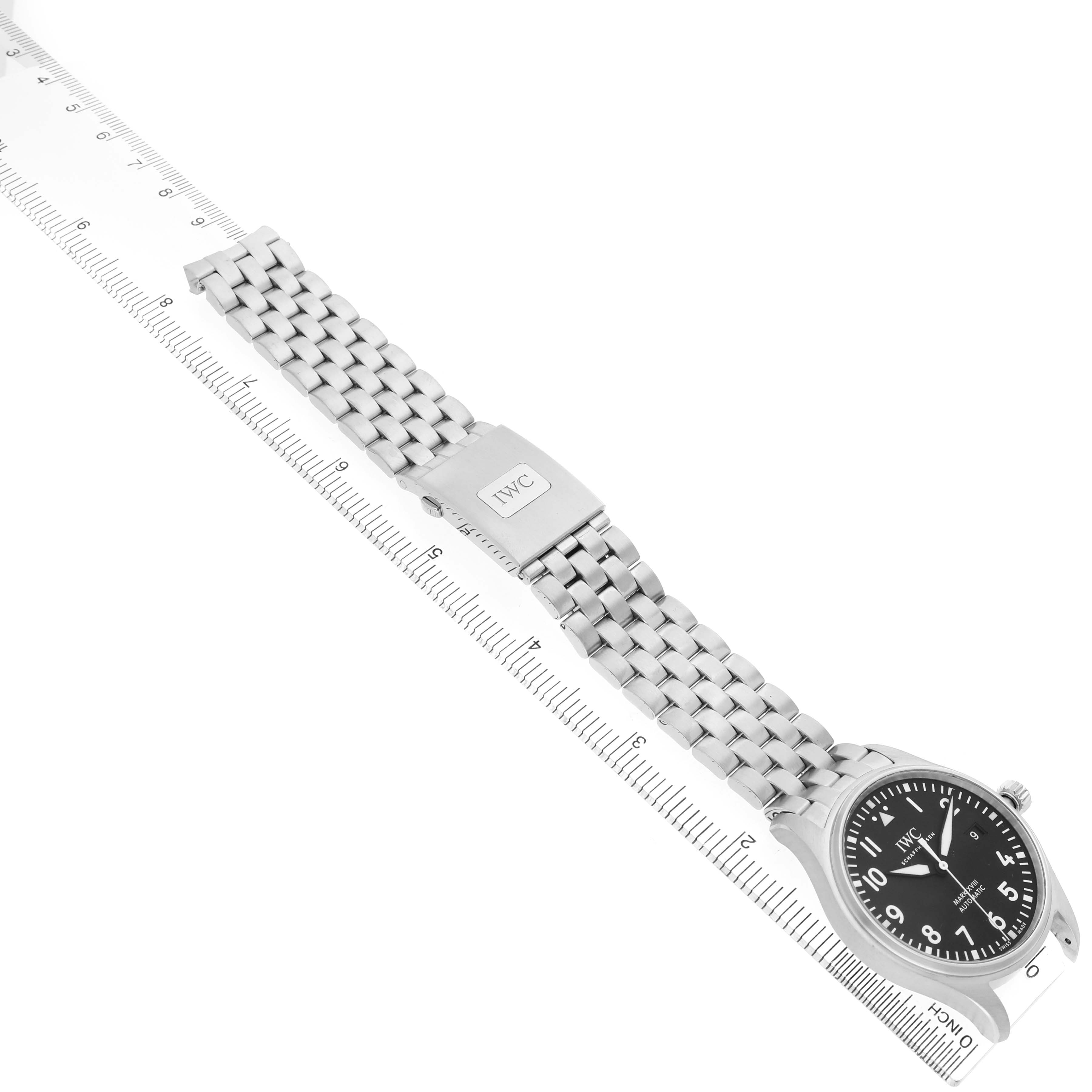 The IWC Pilot IW327015 Men's Stainless Steel Black Dial watch is shown from an angled side view, displaying the face, bracelet, and clasp alongside a ruler for scale.