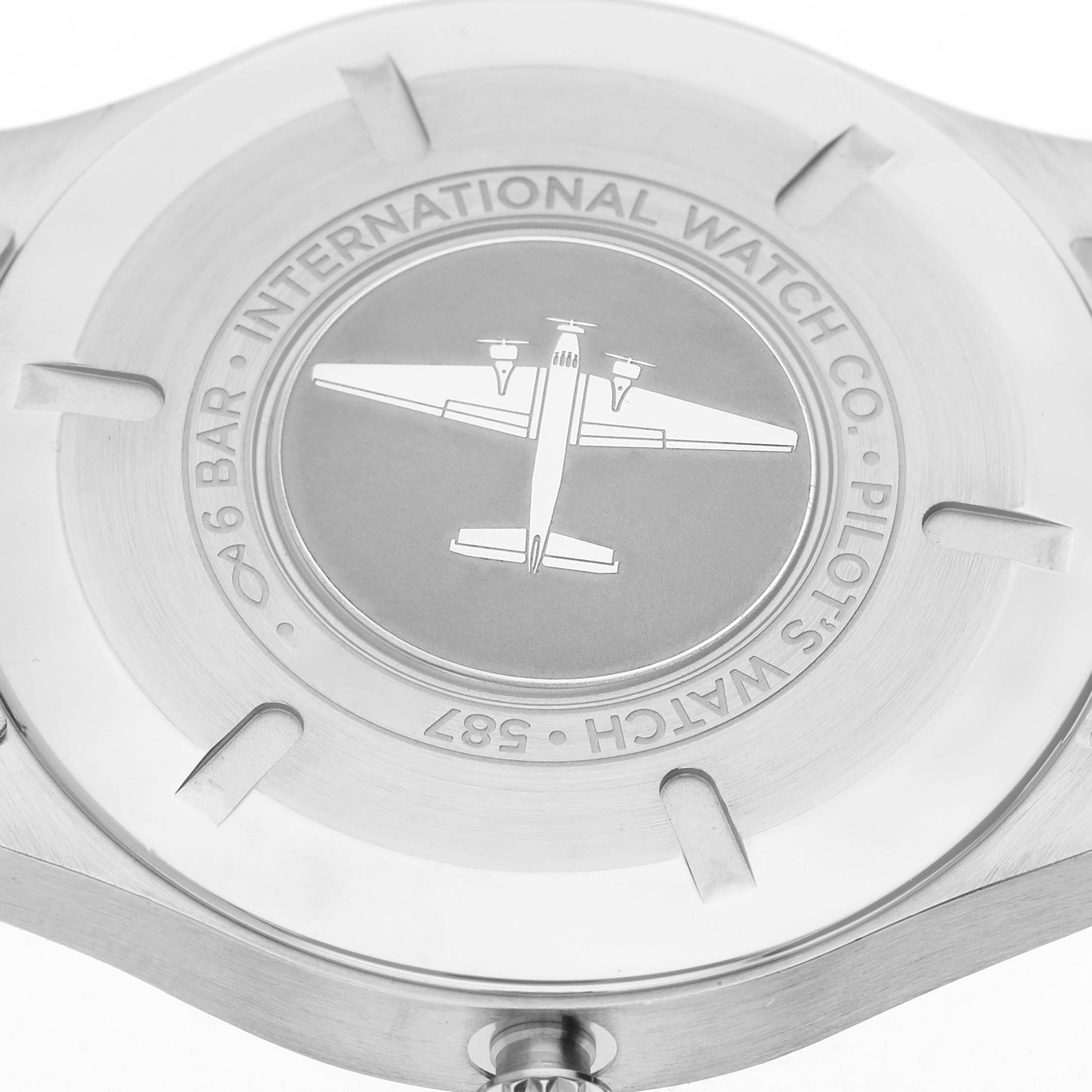 The image shows the back case of an IWC Pilot IW327015 Men's Stainless Steel Black Dial model watch, featuring an engraved airplane design.