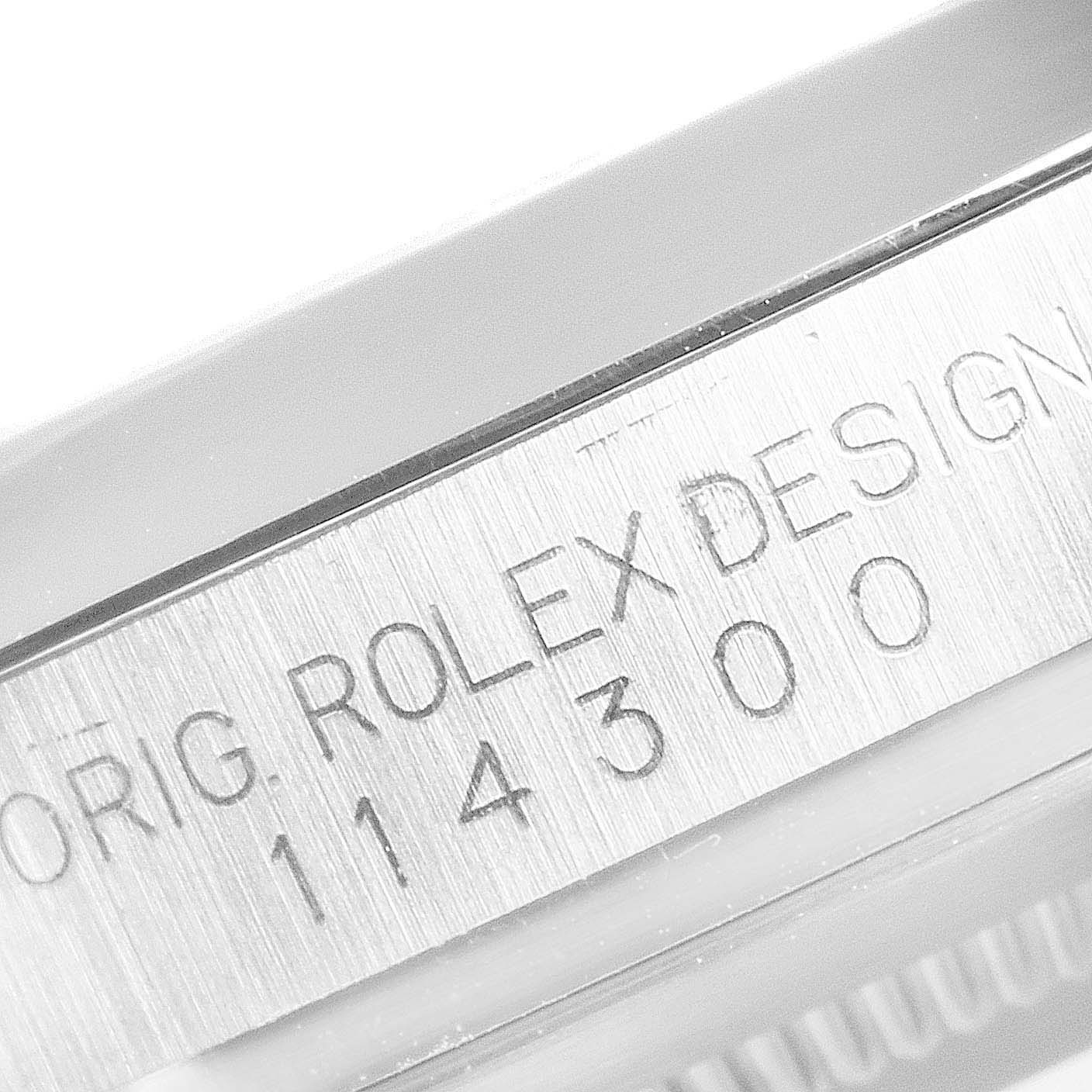 The image shows a close-up of the engraved model number and "Rolex Design" text on the Oyster Perpetual Rolex watch.