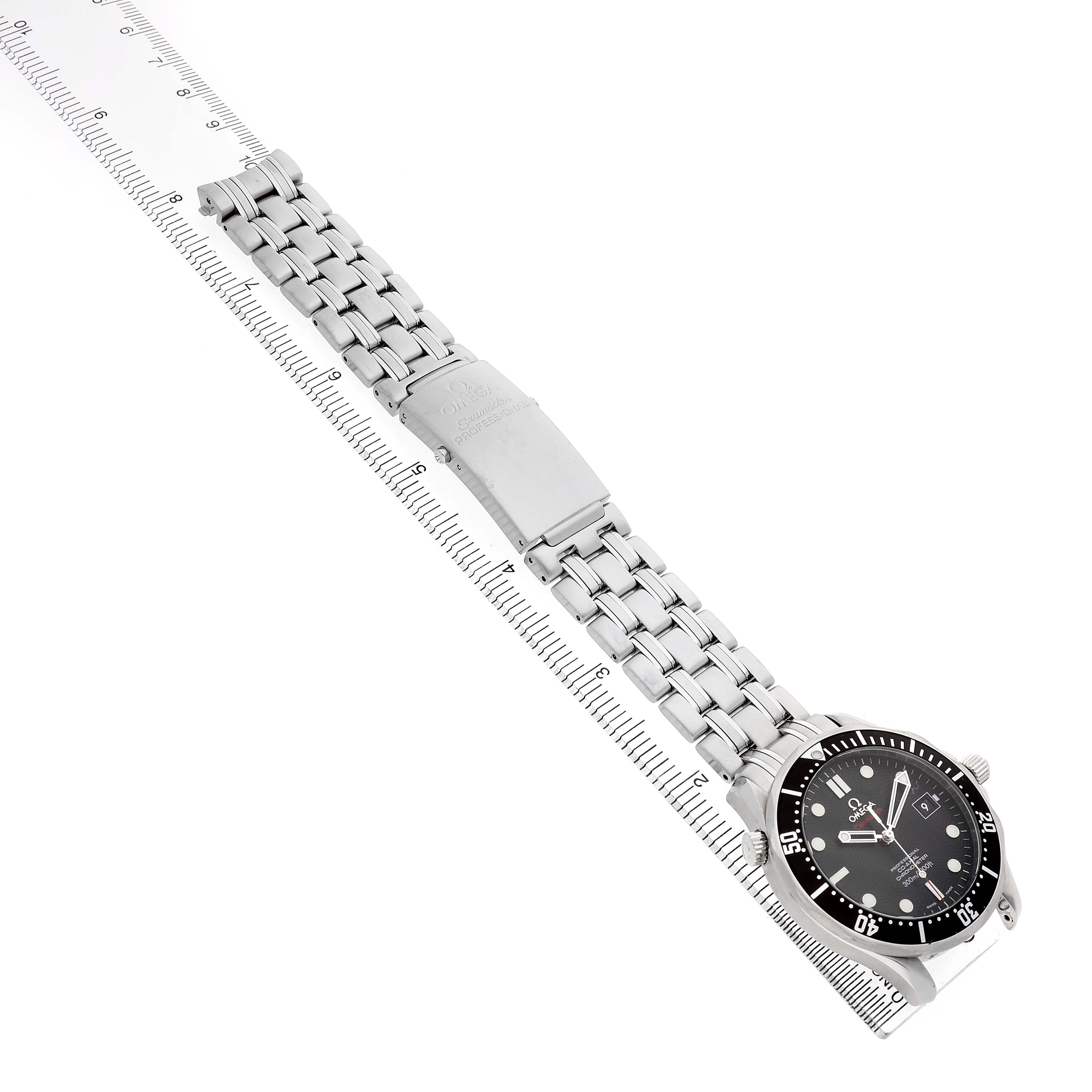 The Omega Seamaster 212.30.41.20.01.002 Men's Stainless Steel Black Dial watch is shown from an overhead angle, highlighting the face, bracelet, and clasp alongside a ruler for scale.