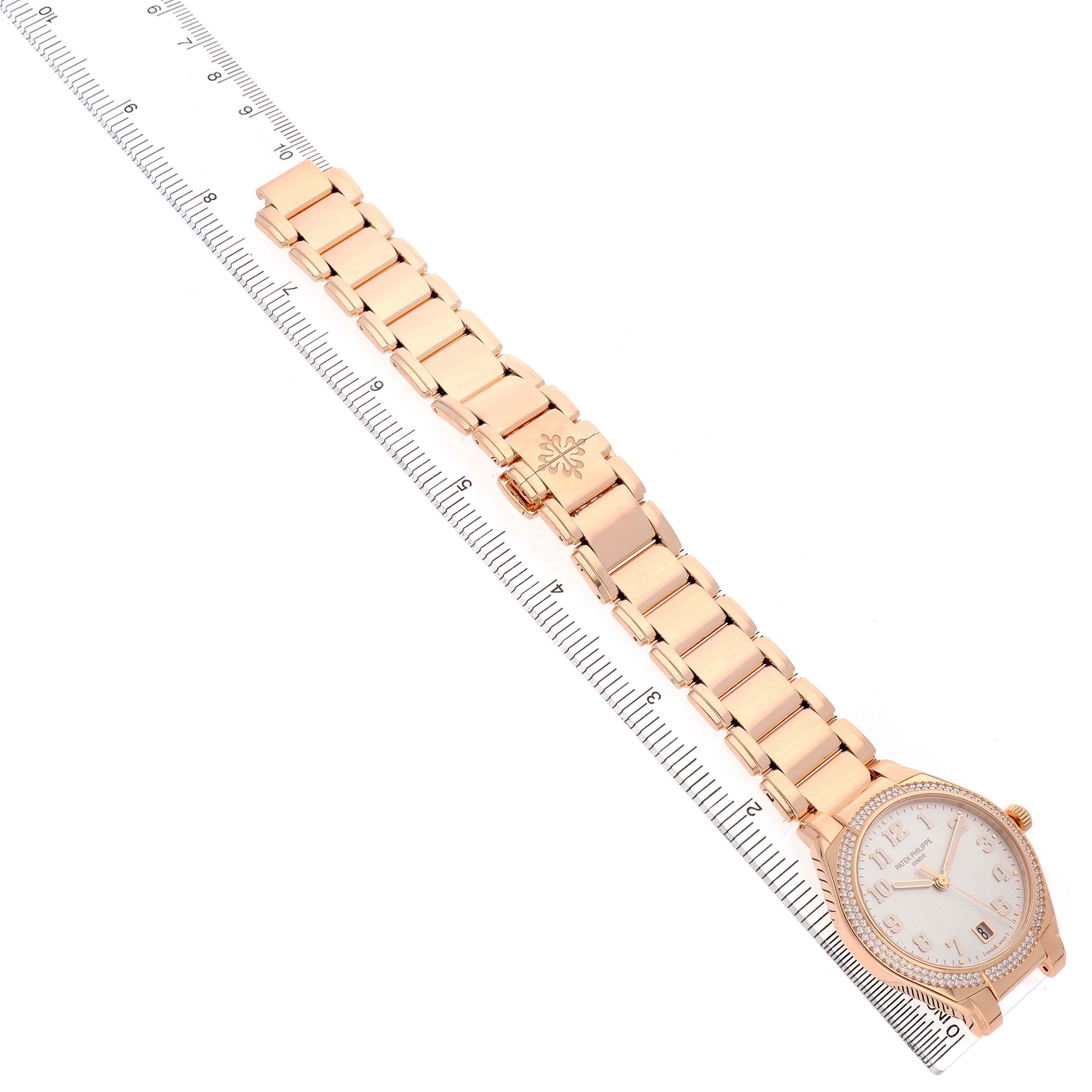 The Patek Philippe Twenty-4 7300/1200R-010 Women's Rose Gold Silver Dial watch is shown from a top-down angle, featuring the full bracelet, clasp, and watch face next to a ruler.