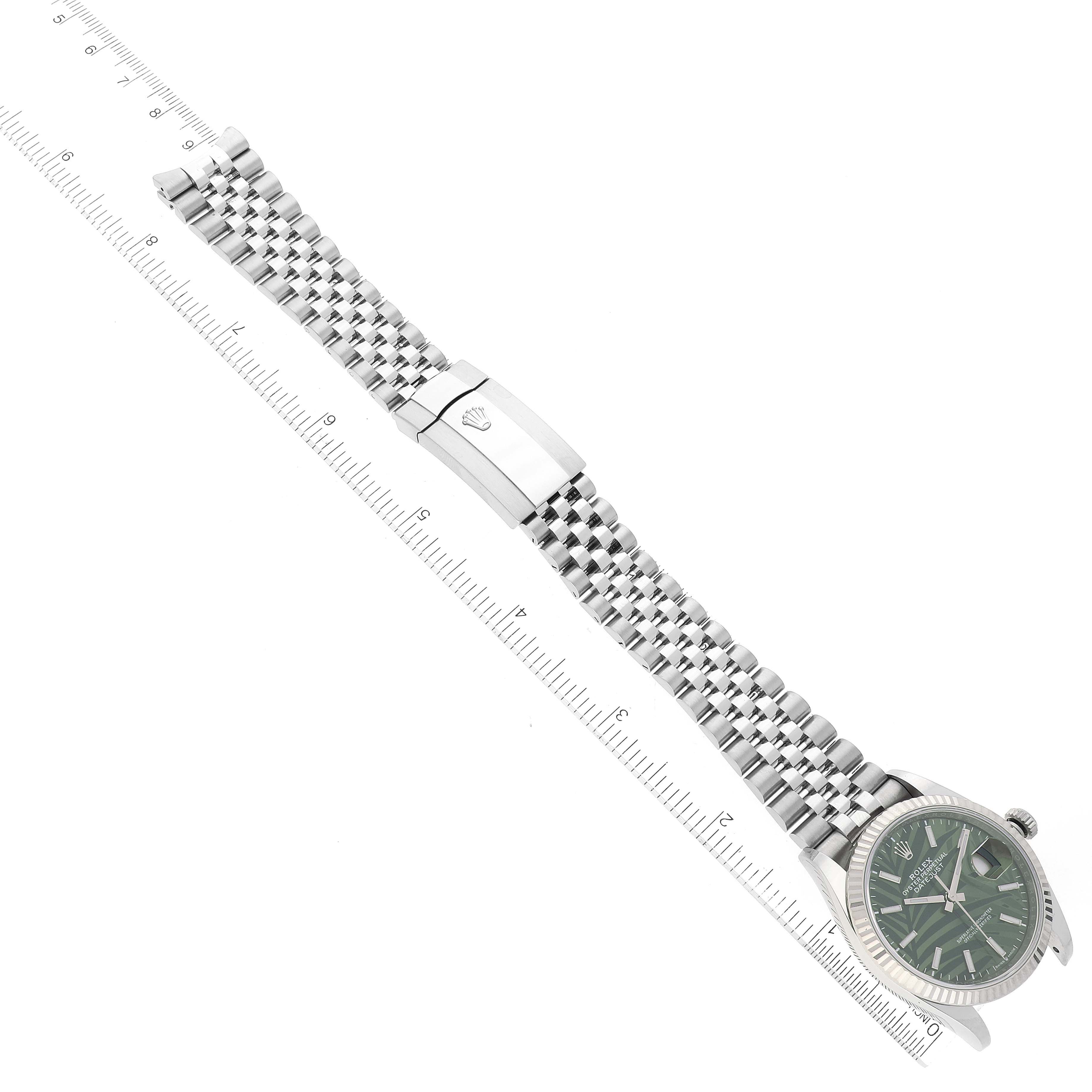 The image shows a Rolex Datejust 126234 Men's Stainless Steel Green Dial 126234 Men's Stainless Steel Green Dial watch, viewed from above, featuring its dial, bezel, bracelet, and clasp positioned next to a ruler.