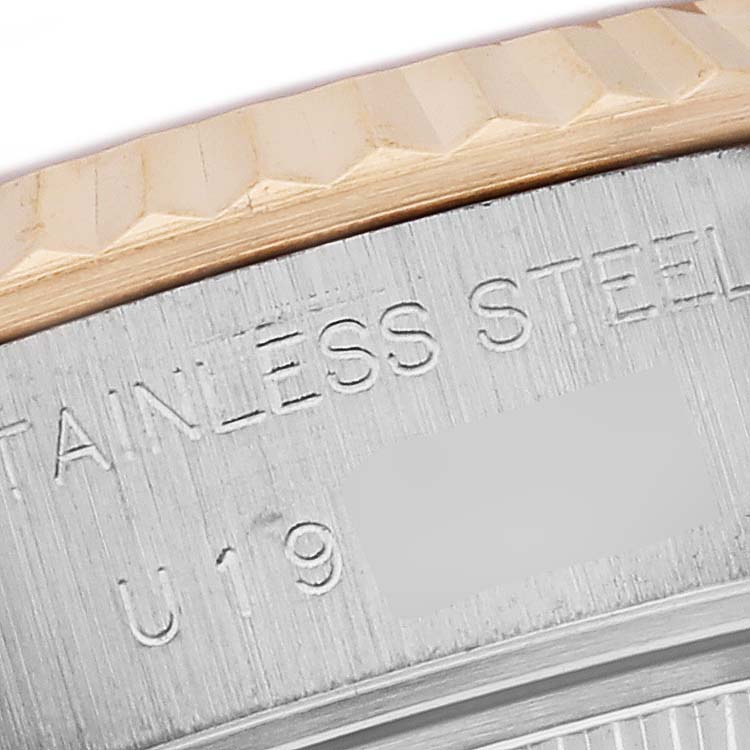 This close-up image of a Rolex Datejust 69173 Women's Steel and Gold (two tone) White Dial 69173 Women's Steel and Gold (two tone) White Dial watch shows part of the fluted bezel and engraved text on the stainless steel case back.