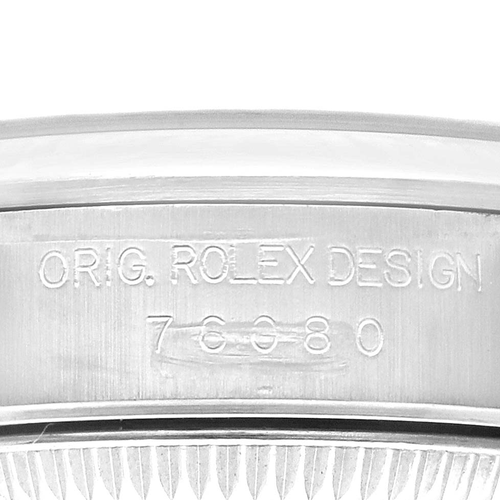Close-up view of the side of a Rolex Oyster Perpetual 76080 Women's Stainless Steel Pink Dial 76080 Women's Stainless Steel Pink Dial watch case, showing the engraved model number and "ORIG. ROLEX DESIGN" text.