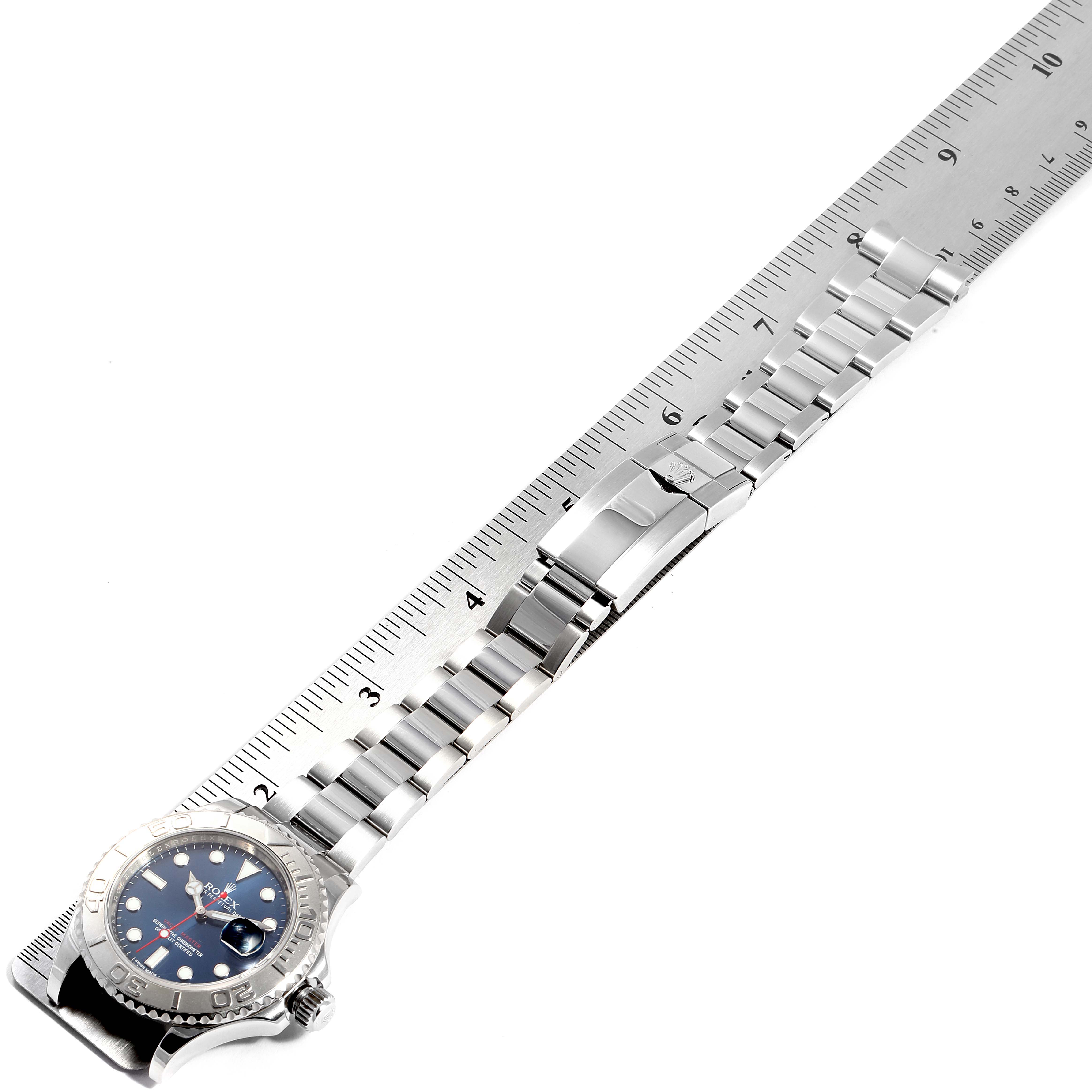 The image shows a Rolex Yacht-Master 116622 Men
s Stainless Steel Blue Dial 116622 Men
s Stainless Steel Blue Dial watch laid flat next to a ruler, highlighting the watch
s bracelet and clasp.