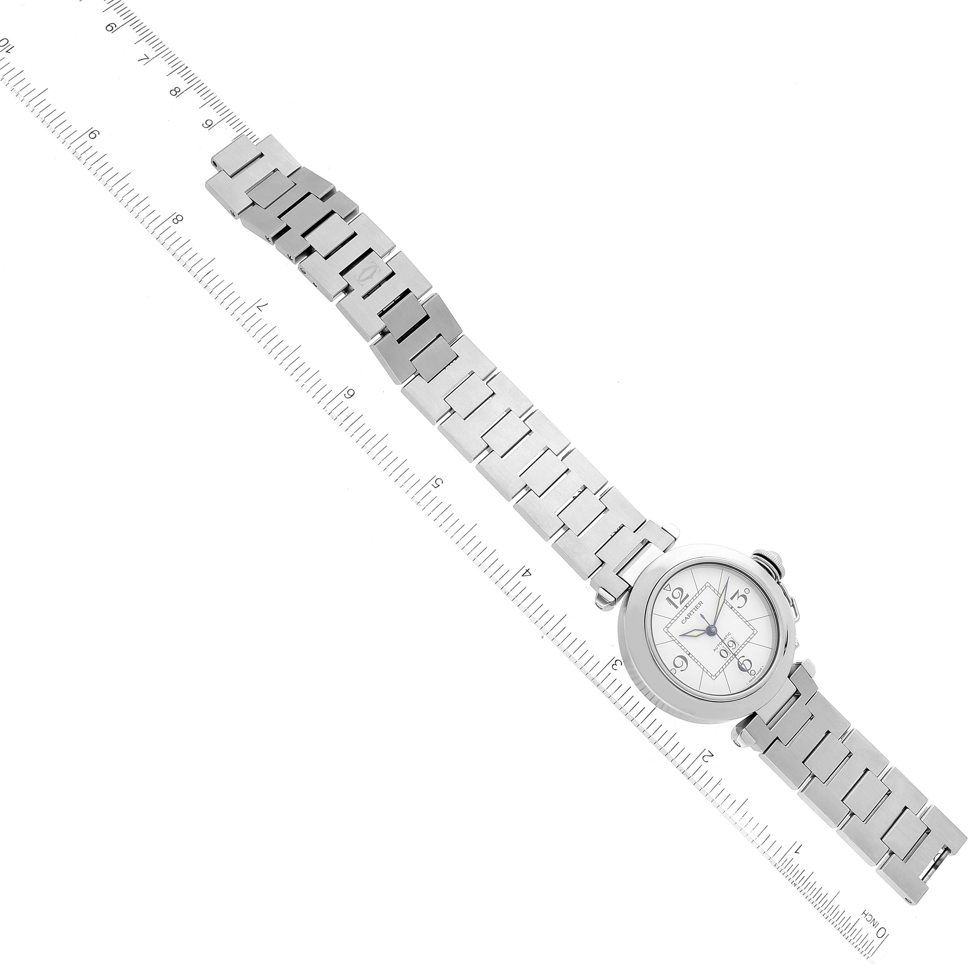 The Cartier Pasha W31055M7 Men's Stainless Steel White Dial W31055M7 Men's Stainless Steel White Dial watch is shown from a top-down angle, with the face and entire metal bracelet visible along with a ruler for scale.
