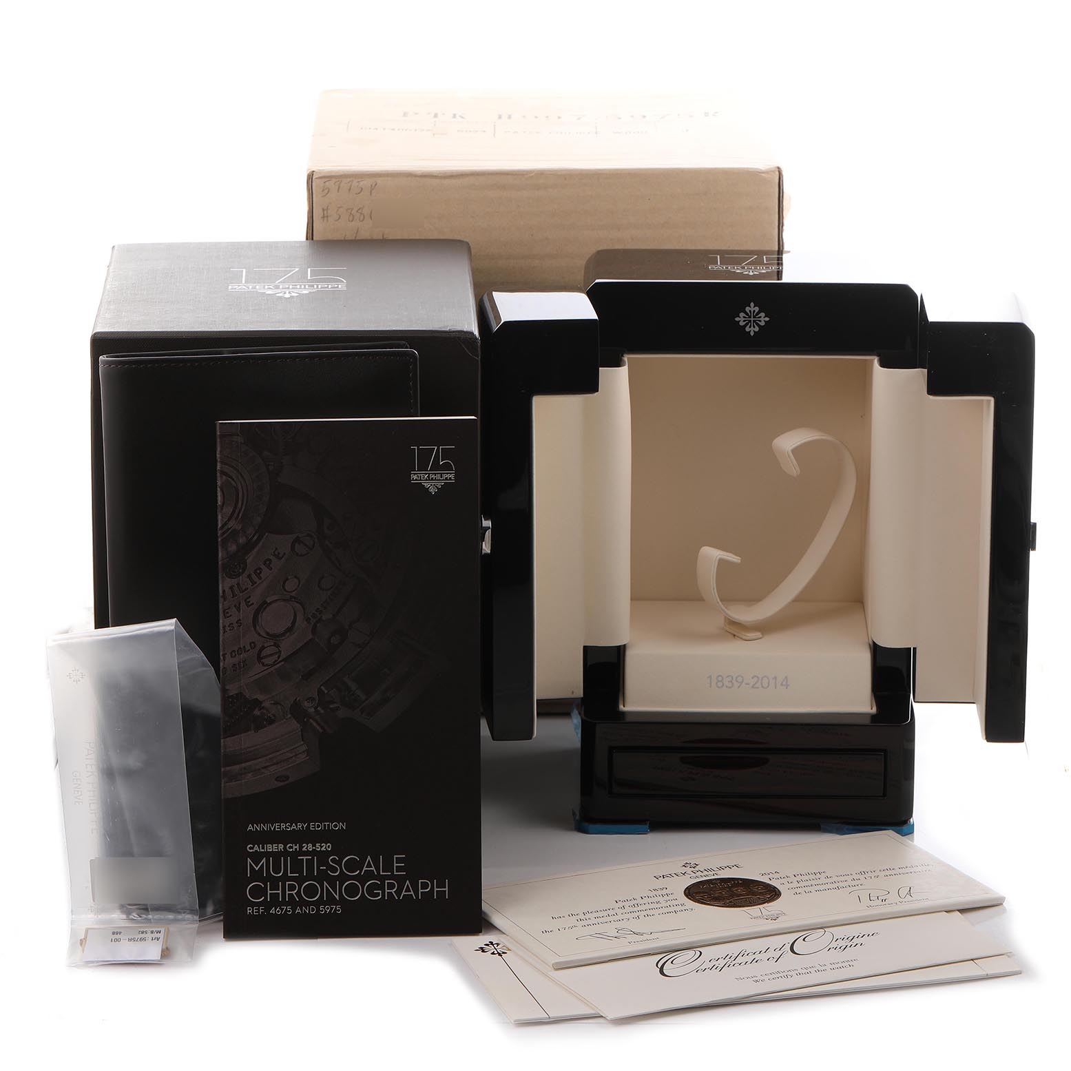 The image shows the packaging and accessories for a Patek Philippe Complications 5975R-001 Men
s Rose Gold Silver Dial 5975R-001 Men
s Rose Gold Silver Dial model, including the box, certificate, and booklet.