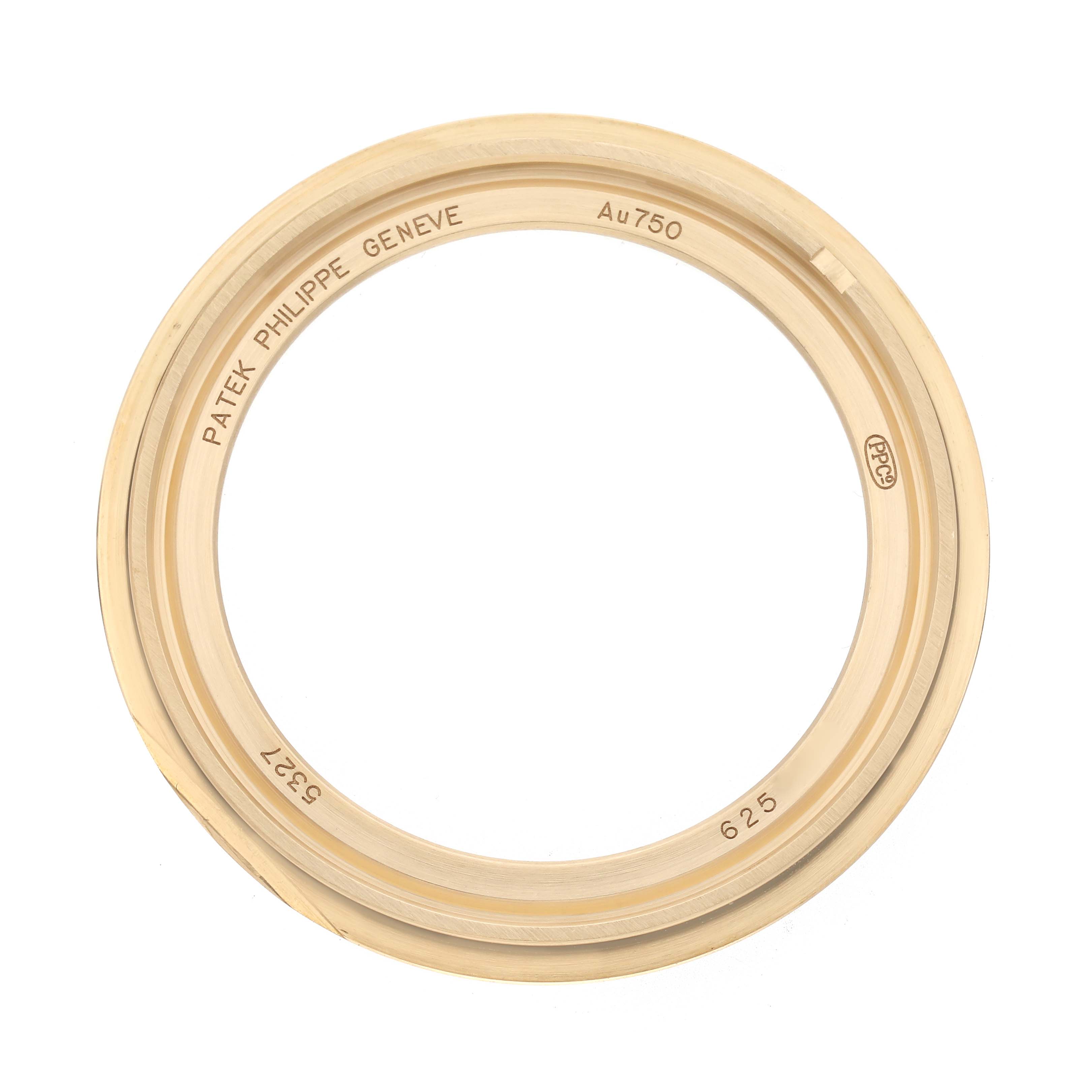 The image shows the bezel of a Patek Philippe Complications 5327J Men
s Yellow Gold Beige Dial 5327J Men
s Yellow Gold Beige Dial watch from a top-down angle, displaying engravings and gold finish details.