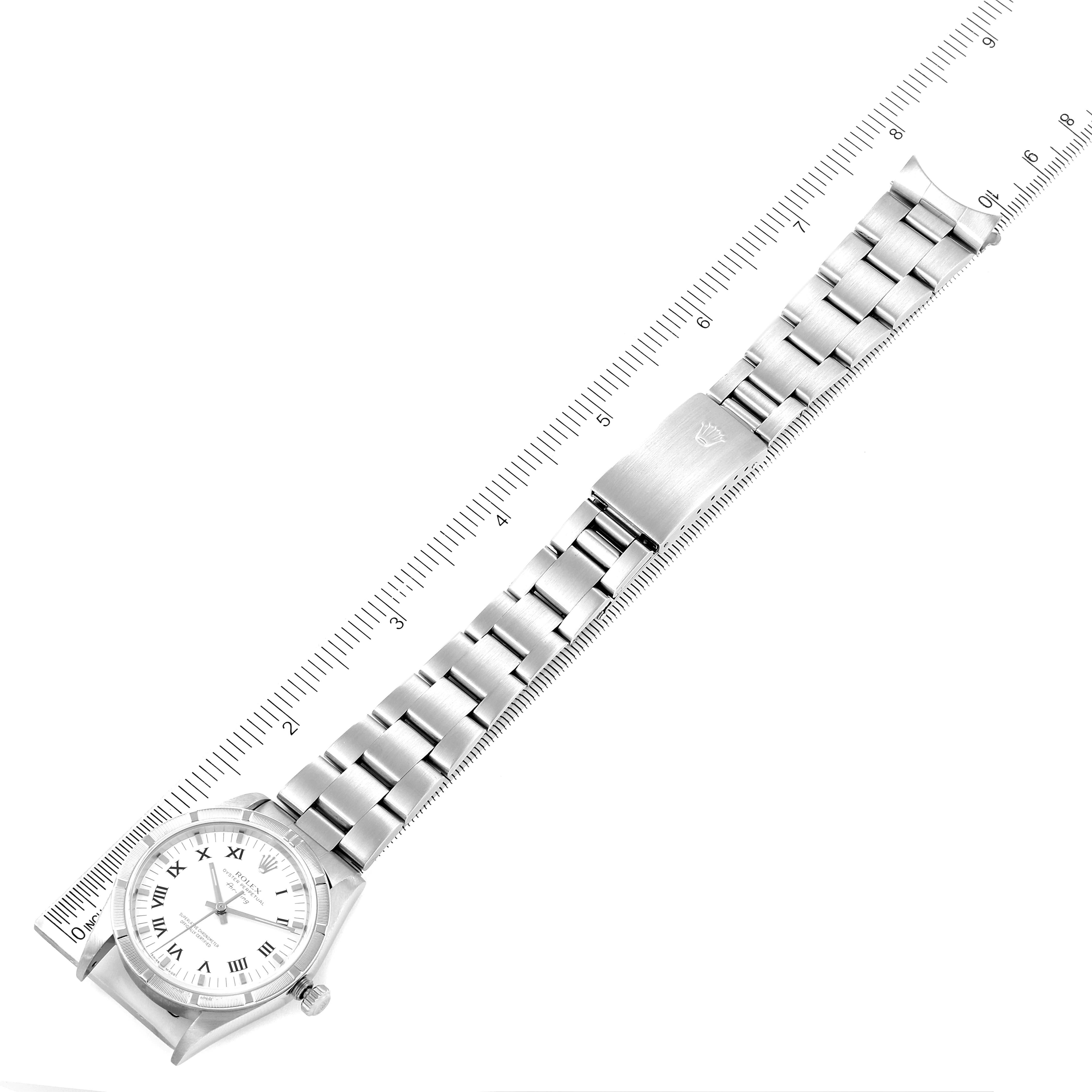 The Rolex Air-King 14010 Men's Stainless Steel White Dial 14010 Men's Stainless Steel White Dial watch is shown from an overhead angle with a prominent view of its face, bracelet, and clasp next to a ruler.