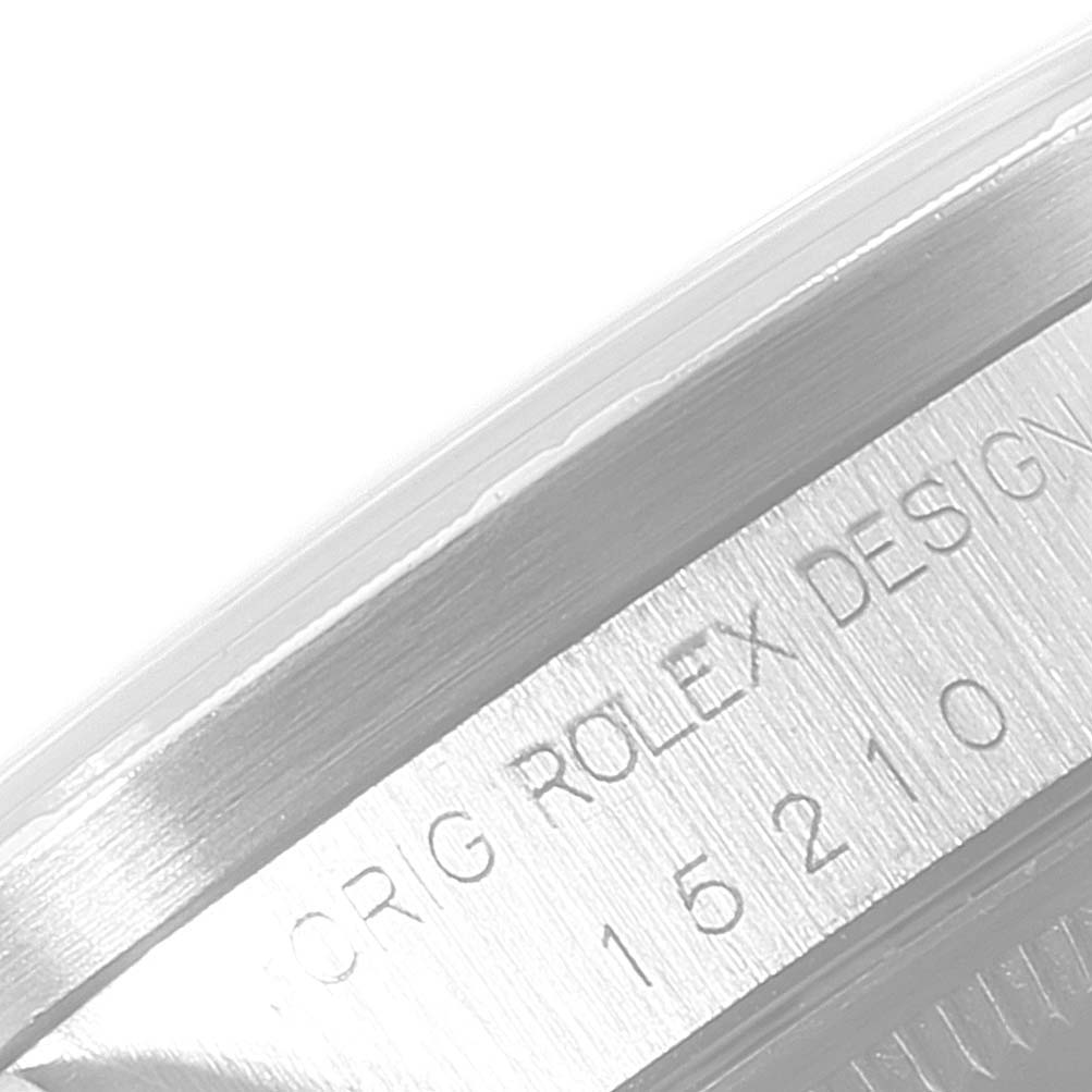 The image shows a close-up of the case side and engraving of a Rolex Date 15210 Men's Stainless Steel Blue Dial 15210 Men's Stainless Steel Blue Dial model watch, displaying its serial numbers.