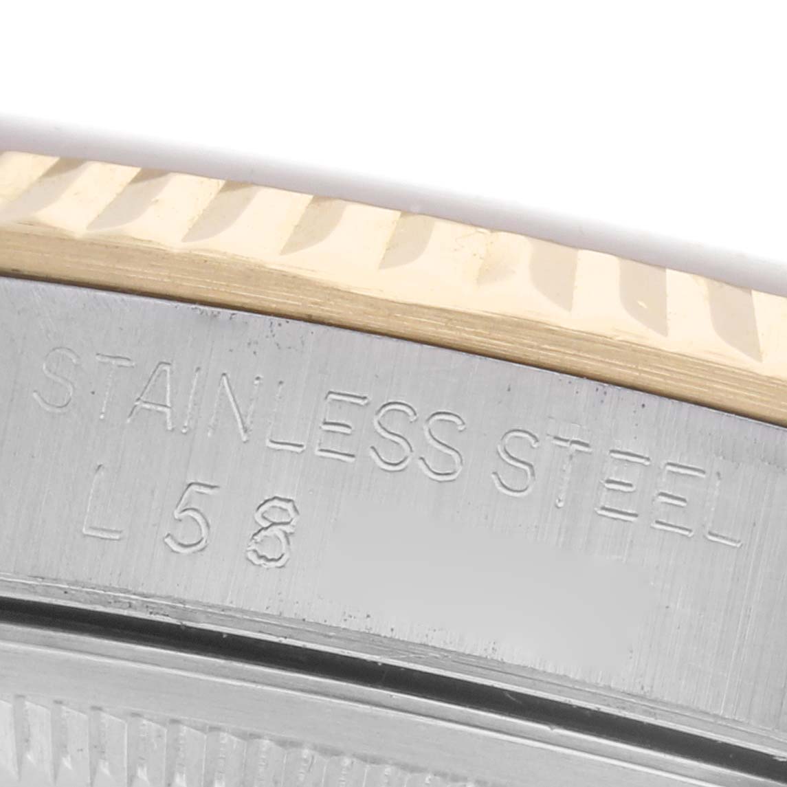 The image shows a close-up of the side engraving on a Rolex Datejust 16233 Men
s Steel and Gold (two tone) White Dial 16233 Men
s Steel and Gold (two tone) White Dial
s stainless steel case with part of the fluted bezel.