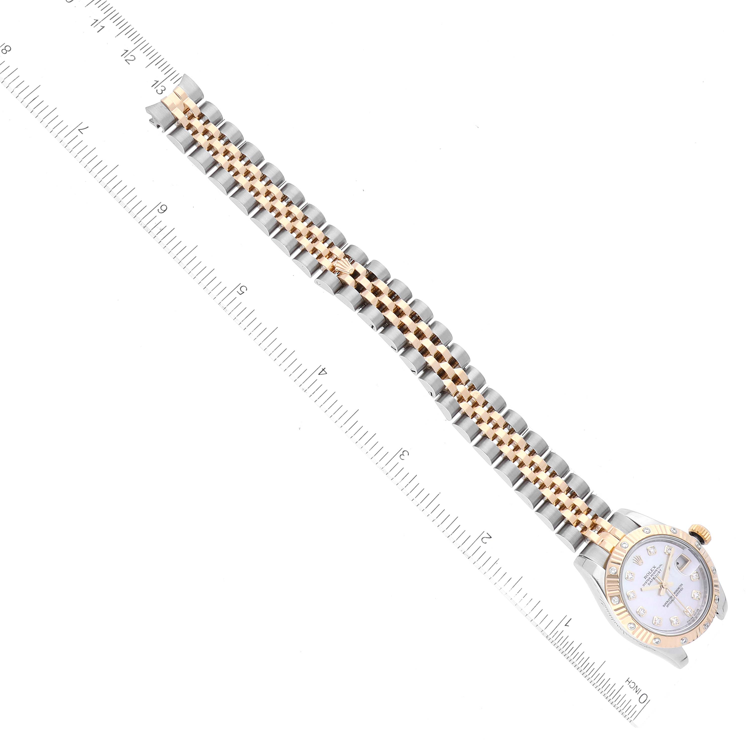 The image shows a top view of a Rolex Datejust 179313 Women's Steel and Gold (two tone) Mother of Pearl Dial 179313 Women's Steel and Gold (two tone) Mother of Pearl Dial watch, highlighting its face and entire metal bracelet alongside a ruler for scale.