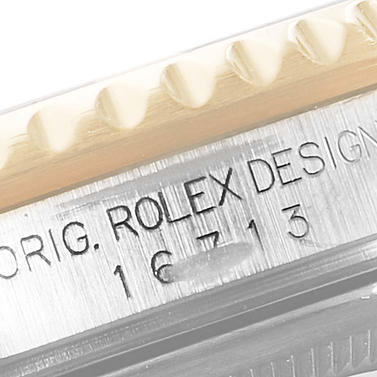 Close-up view showing the engraved text "ROLE" and partial Bezel of a Rolex GMT-Master 16713 Men's Steel and Gold (two tone) Black Dial 16713 Men's Steel and Gold (two tone) Black Dial watch, model 16713.